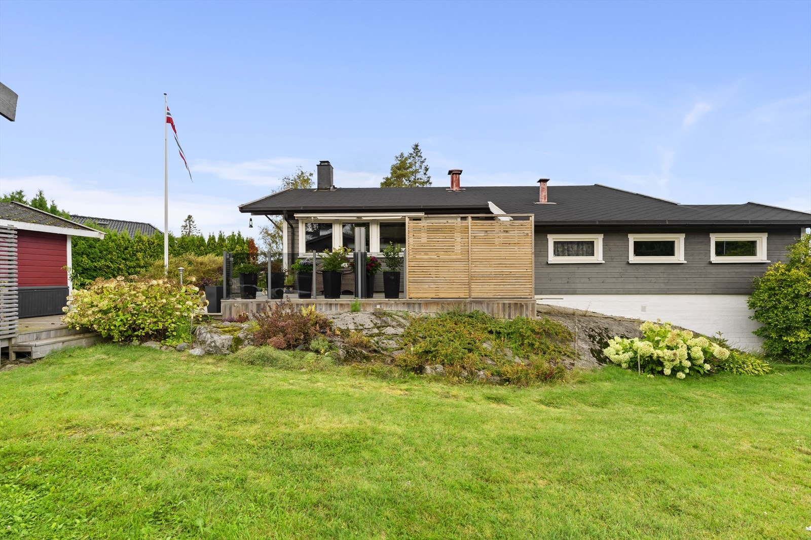 Tomten er pent opparbeidet med gressplen, bed og busker. Galleribilde