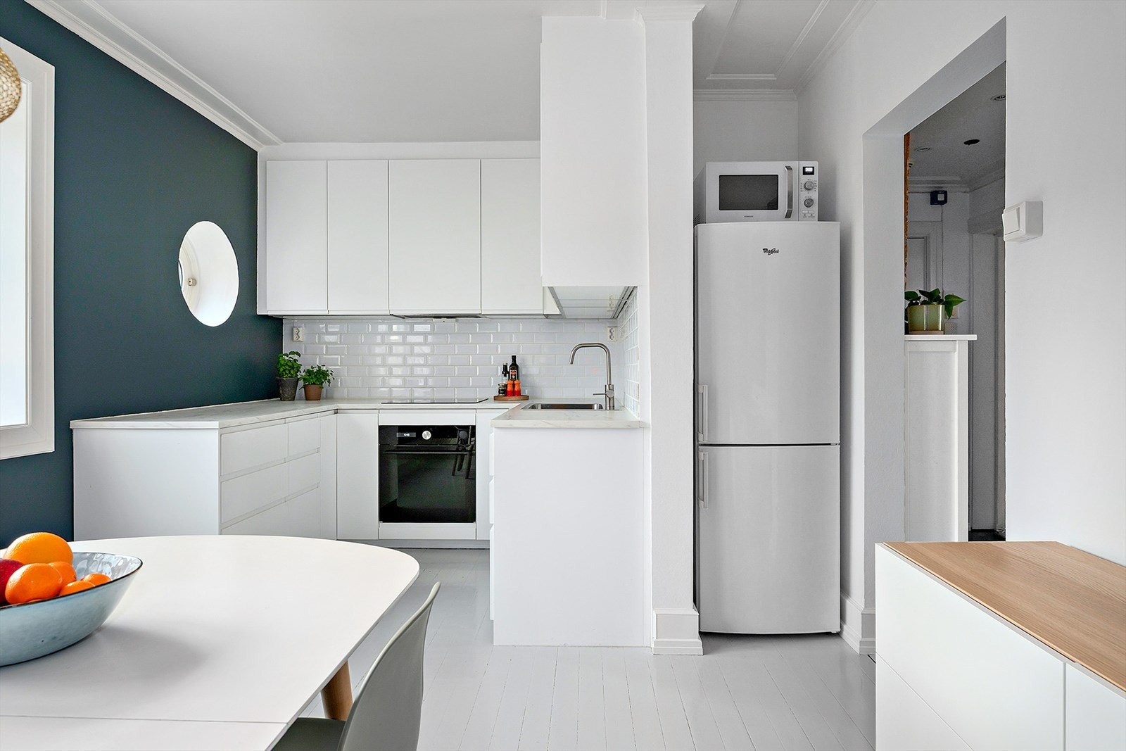 Kjøkkenet har innredning med glatte fronter og laminatbenkeplate med nedfelt kum i rustfritt stål. Det er montert ventilator og fliser på vegg over benkeskap. Galleribilde