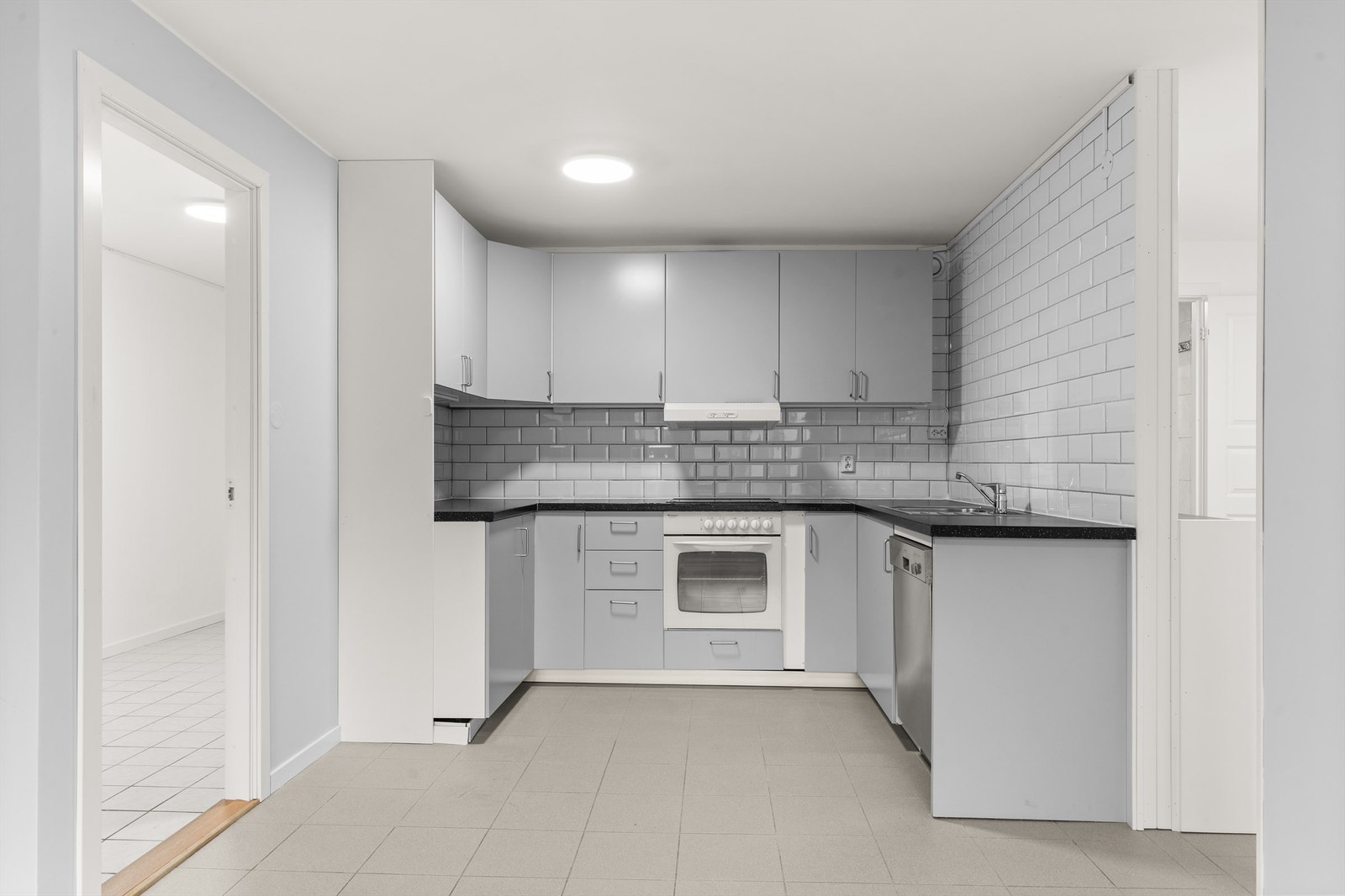 Kjøkkeninnredning med glatte fronter og laminat benkeplate med nedfelt vaskekum. Av integrerte hvitevarer er det platetopp og stekeovn. Kullfilterventilator over kokeplass. Galleribilde