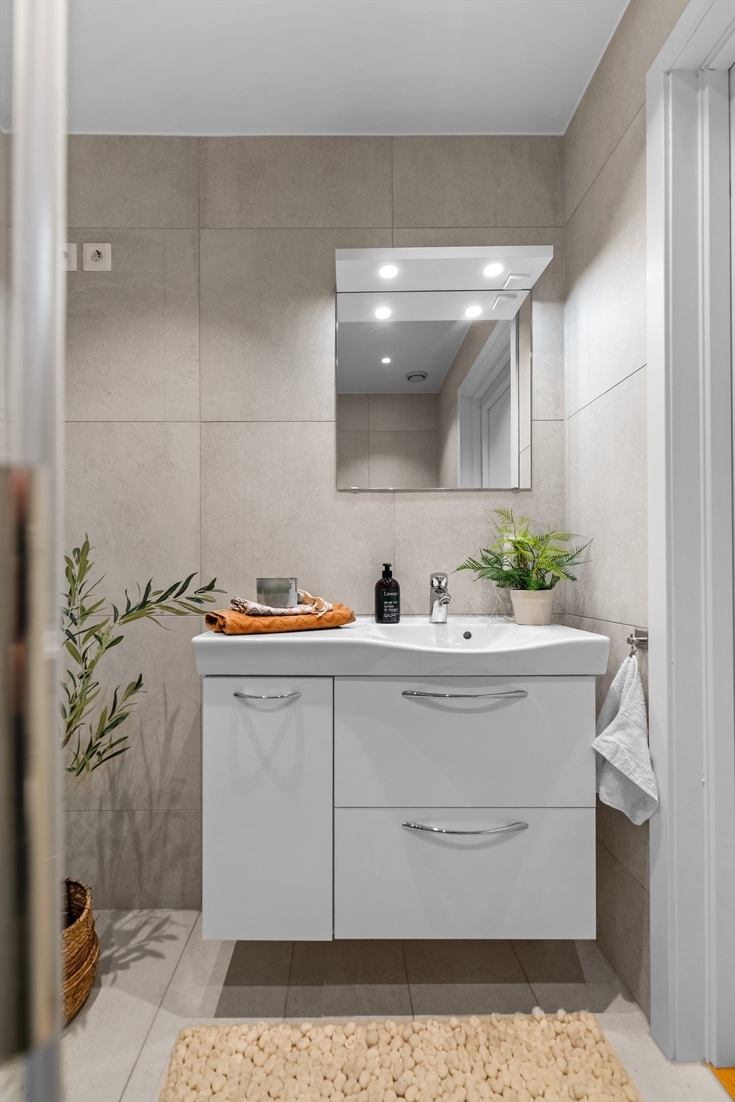 Servant i baderomsinnredning med oppbevaringsplass i skap og skuffer. Speil med belysning er montert over. Galleribilde