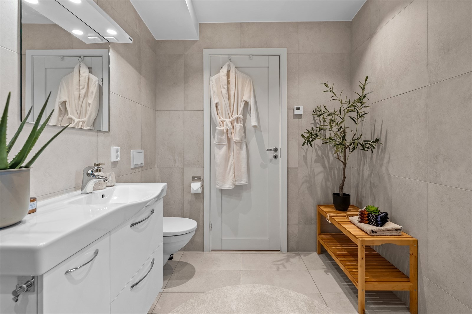 Badet er innredet med vegghengt toalett, servant i baderomsinnredning og dusjhjørne. Galleribilde