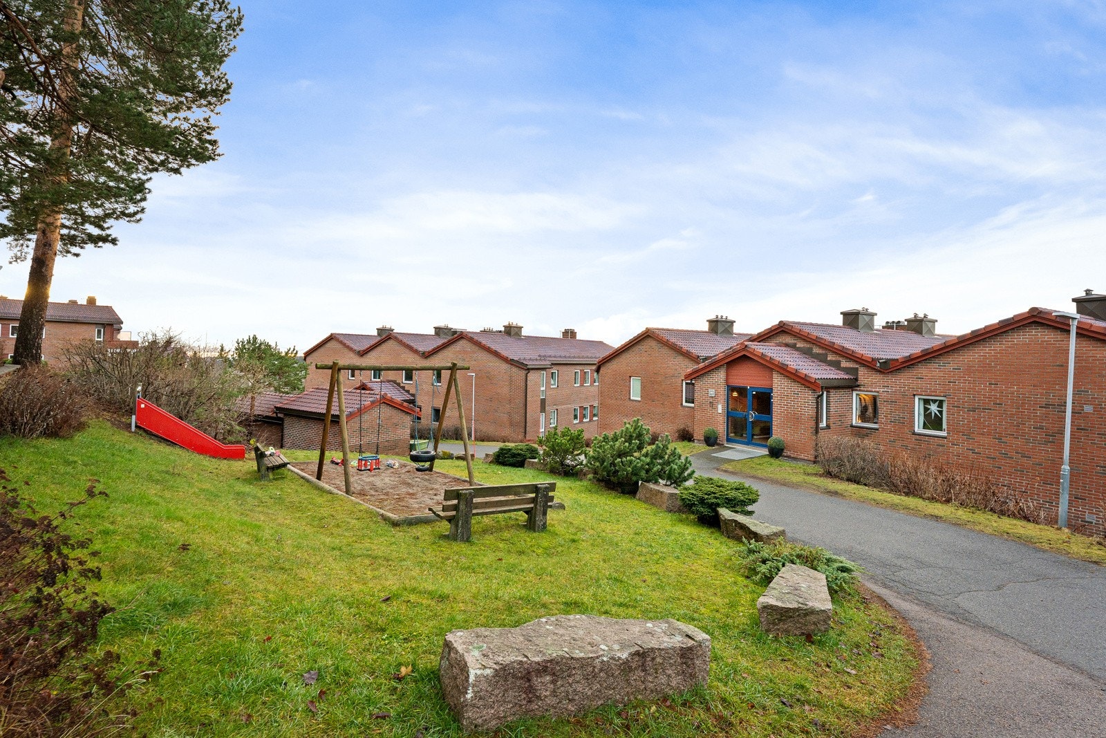 Rundt boligen er det pent opparbeidede grøntarealer med lekeplass og sittegrupper Galleribilde