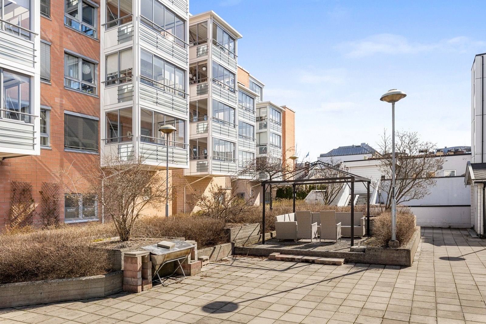 Hyggelig fellesområde i borettslaget med steinbelagt uteplass med sittegruppe, grill og diverse beplantning. Galleribilde