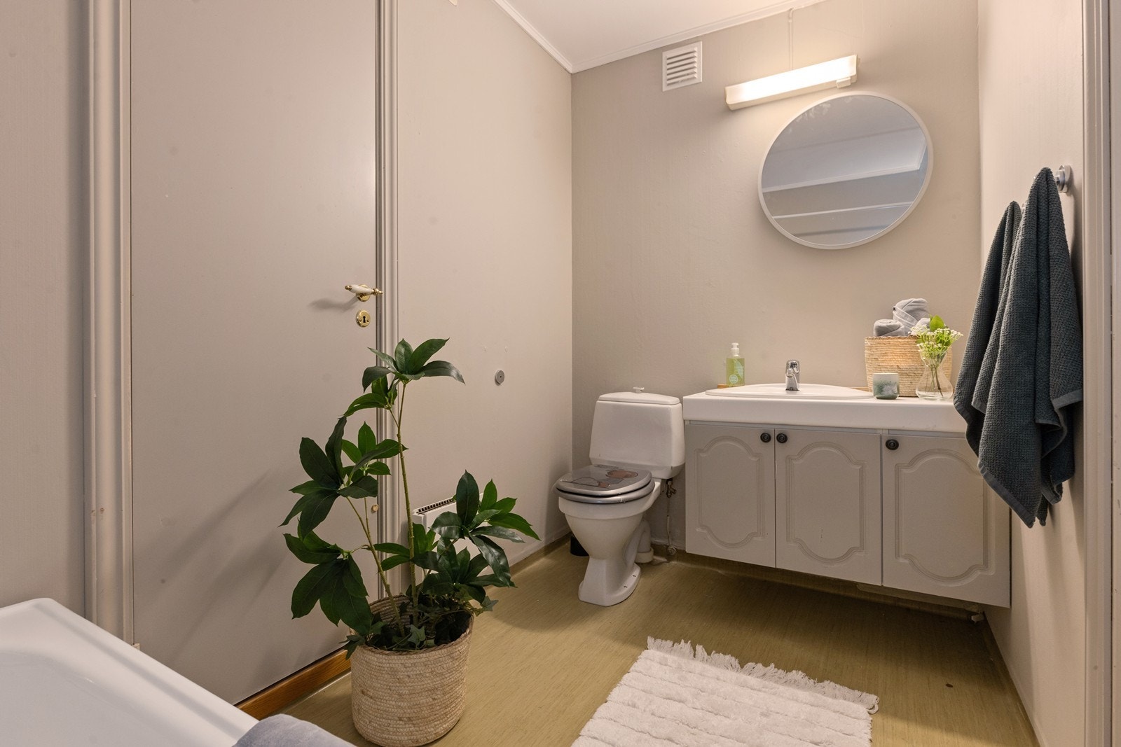 Dette badet er ustyrt med servant med underskap, toalett og badekar med veggmontert armatur Galleribilde