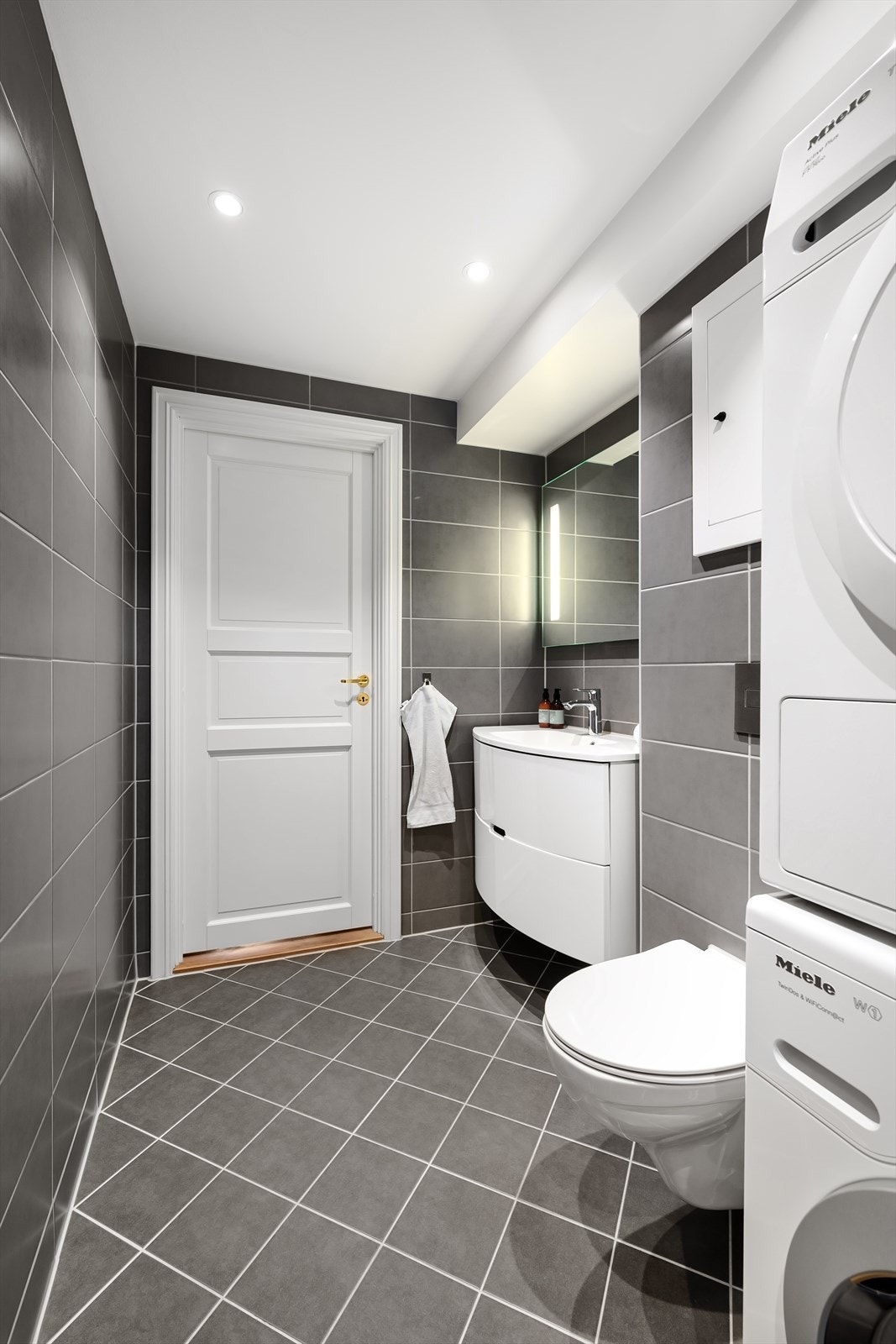 Innredet med dusj, speil med ledlys, servantinnredning med skuffer og veggmontert toalett. Downlights i himling og varmekabler i gulv. Galleribilde