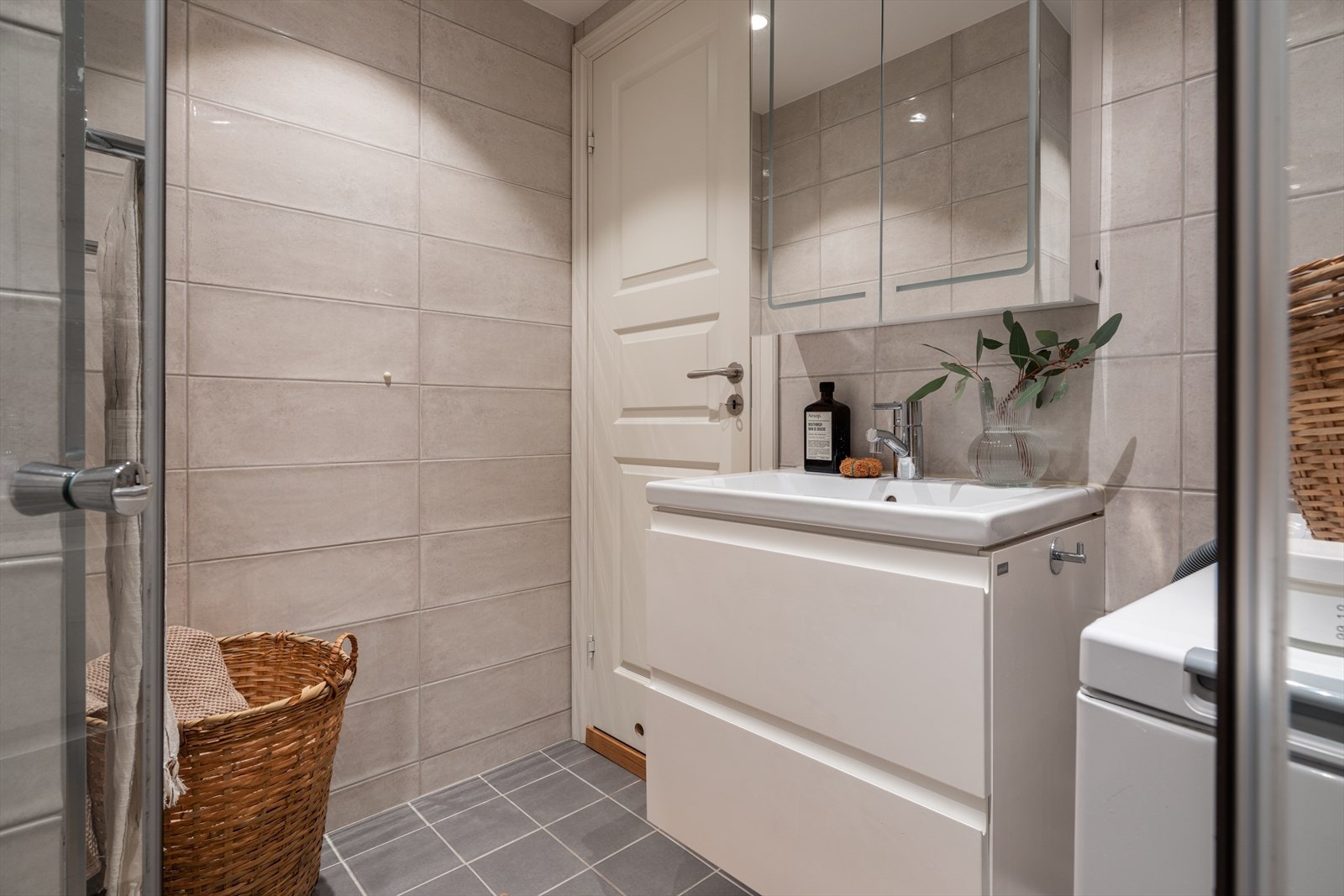 Badet er innredet med servant i skuffeseksjon og speilskap for oppbevaring. Opplegg for vaskemaskin. Galleribilde