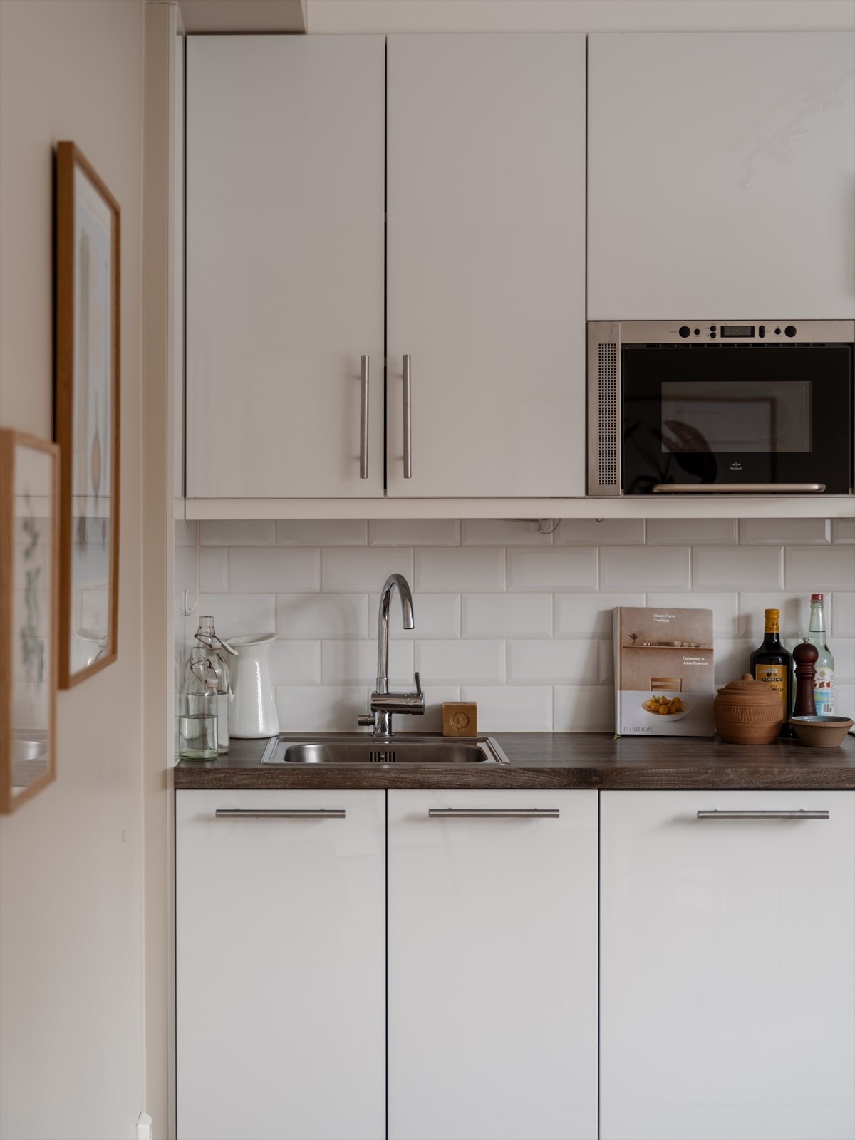 En hvit kjøkkeninnredning med glatte fronter og laminert benkeplate med nedfelt oppvaskkum. Galleribilde