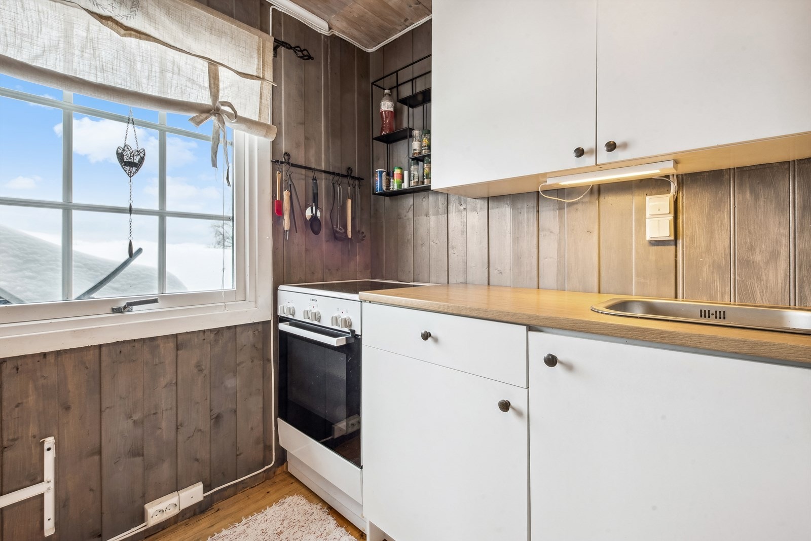 Kjøkkenet er utstyrt med komfyr og kjøleskap. Innredningen har slette fronter og laminert benkeplate. Galleribilde