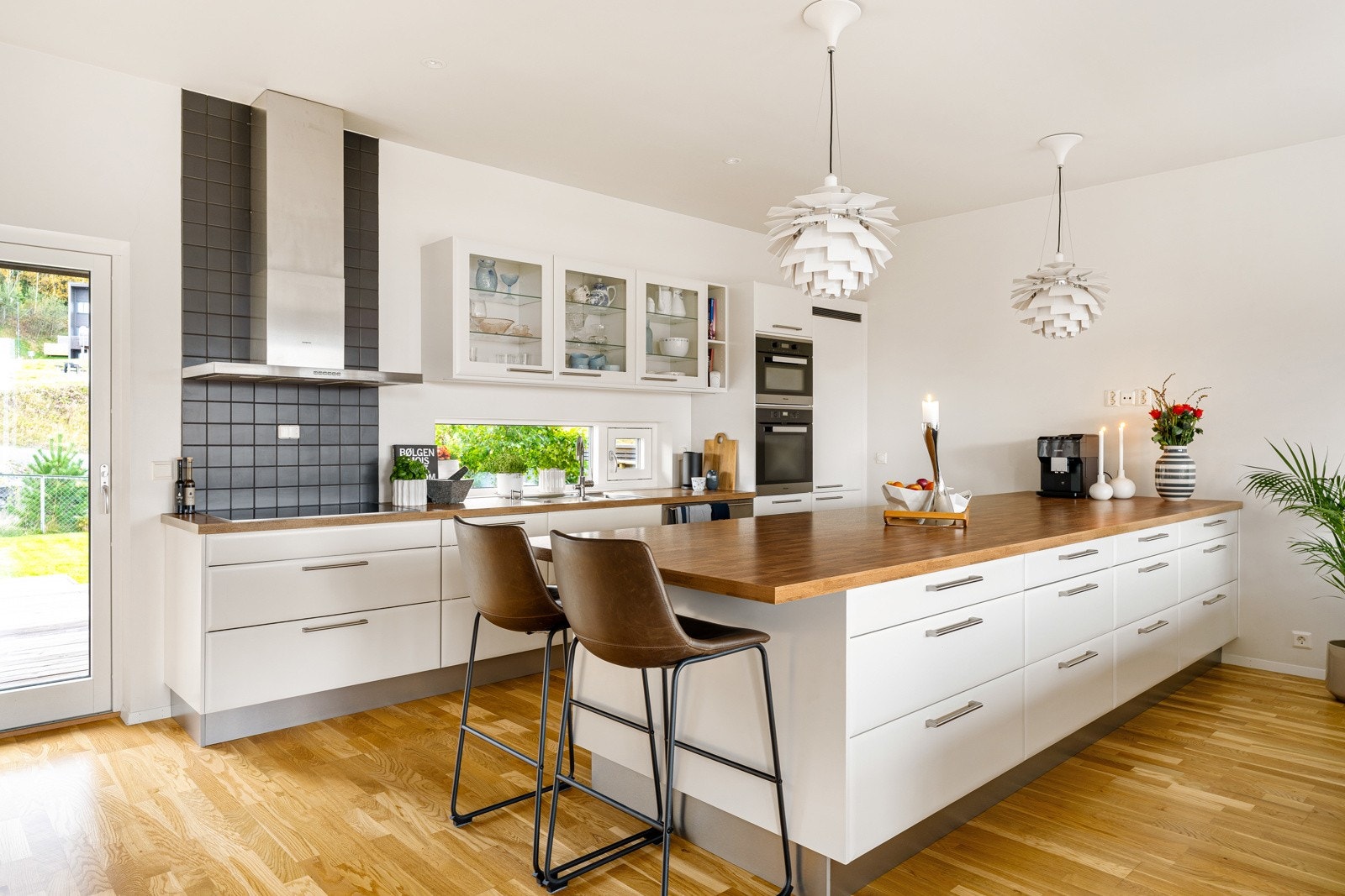 Kjøkkeninnredningen er i hvite fronter, eikefarget benkeplate og har en kjøkkenøy som gir rikelig med benkeplass. Galleribilde