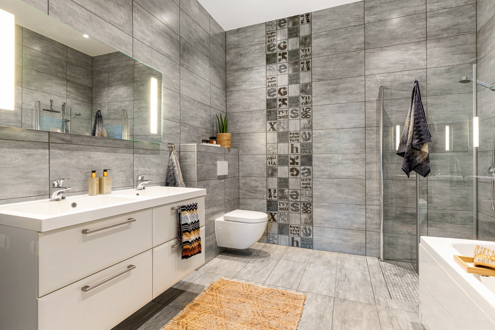 En-suite badet er flislagt på vegger og gulv med grå fliser og har behagelig gulvvarme. Galleribilde