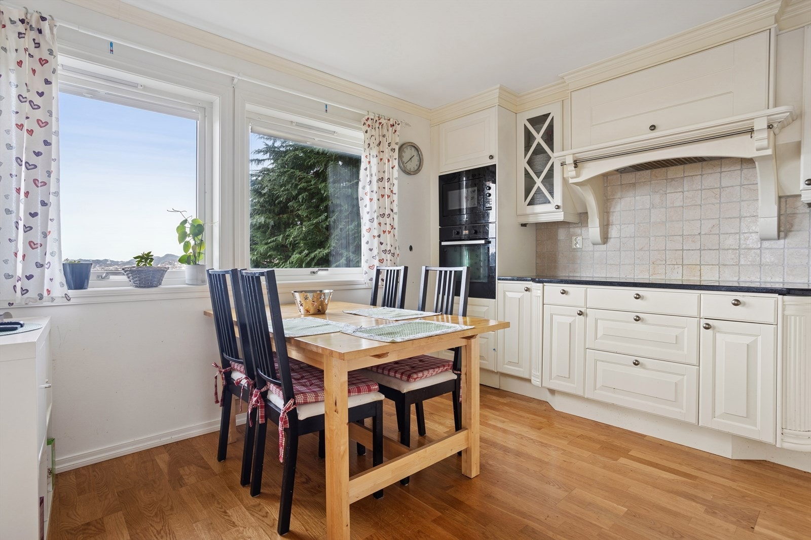 Integrerte hvitevarer som stekeovn, mikrobølgeovn, induksjonstopp, ventilator og kjøle-/fryseskap gir et helhetlig og moderne preg. Marmorfliser mellom benk og overskap setter prikken over i-en. Galleribilde