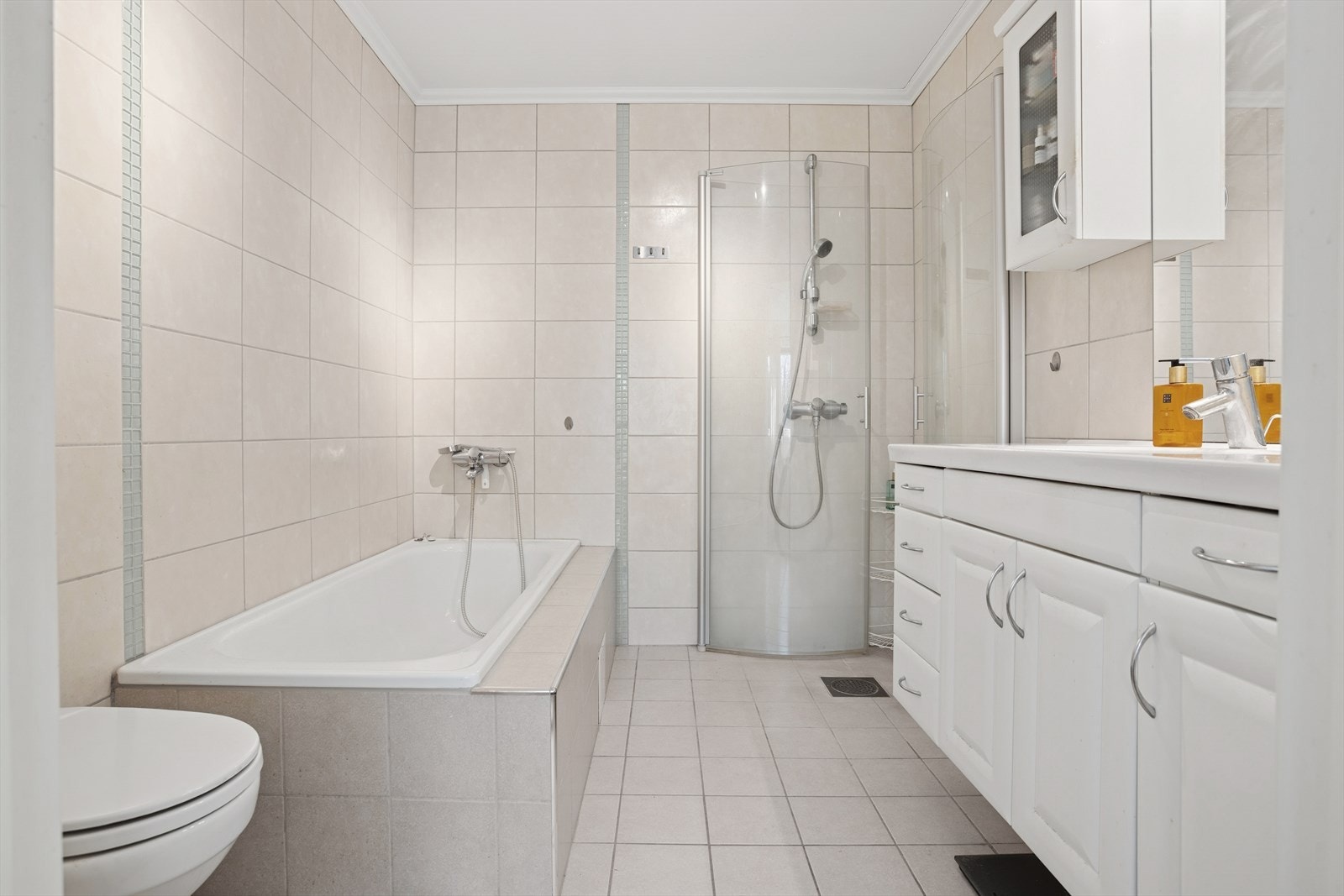 Lyst og lekkert en-suite bad med helflisede overflater og vannbåren gulvvarme som gir god komfort. Galleribilde