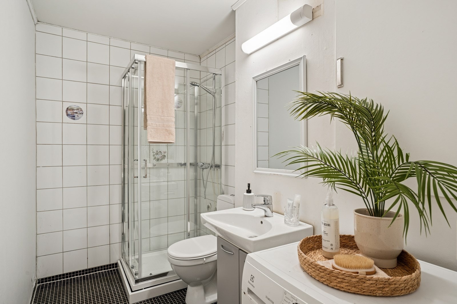 Lyst bad med dusjkabinett, servant og opplegg for vaskemaskin. Galleribilde