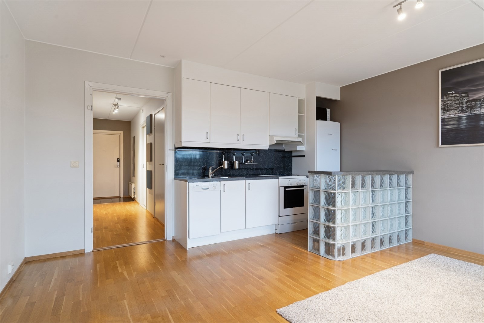 Kjøkken innredet med folierte skrog med slette fronter og laminert benkeplate. Plater på vegg over benkeplate. Galleribilde