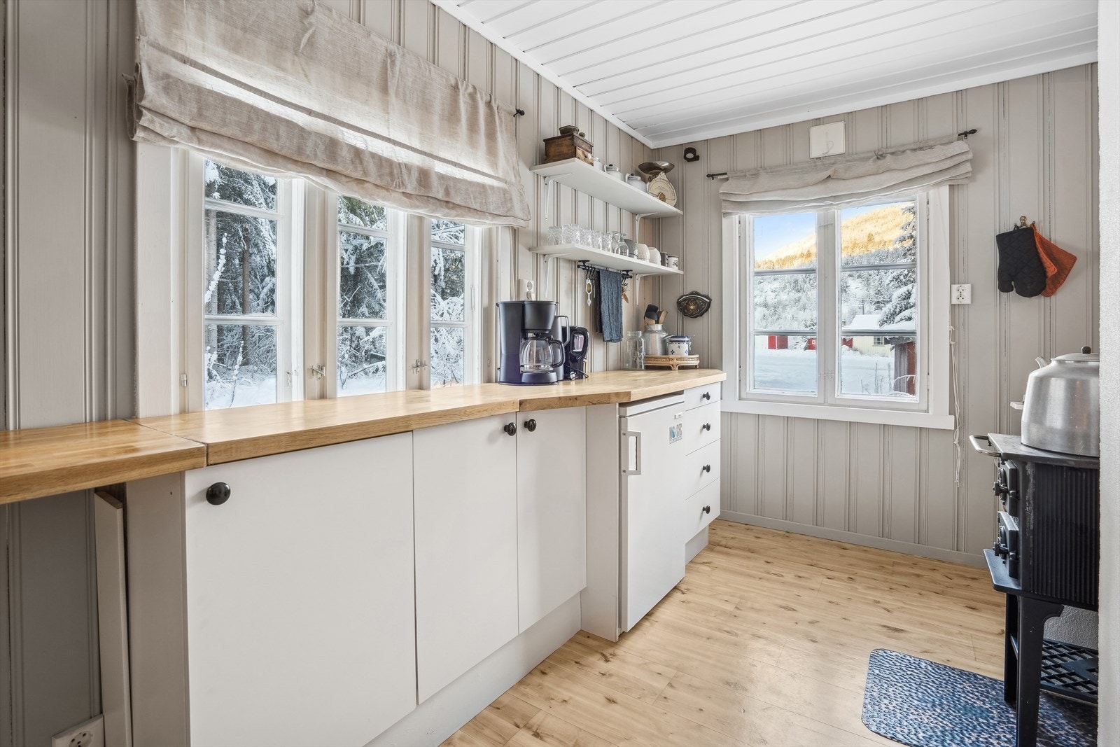 Enkelt hyttekjøkken med innredning med glatte fronter. Benkeplaten er av heltre Galleribilde