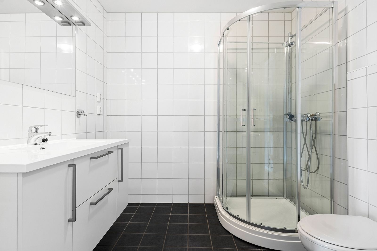 Pent flislagt bad med servant m/skap, dusjkabinett og toalett. Opplegg til vaskemaskin/tørketrommel Galleribilde