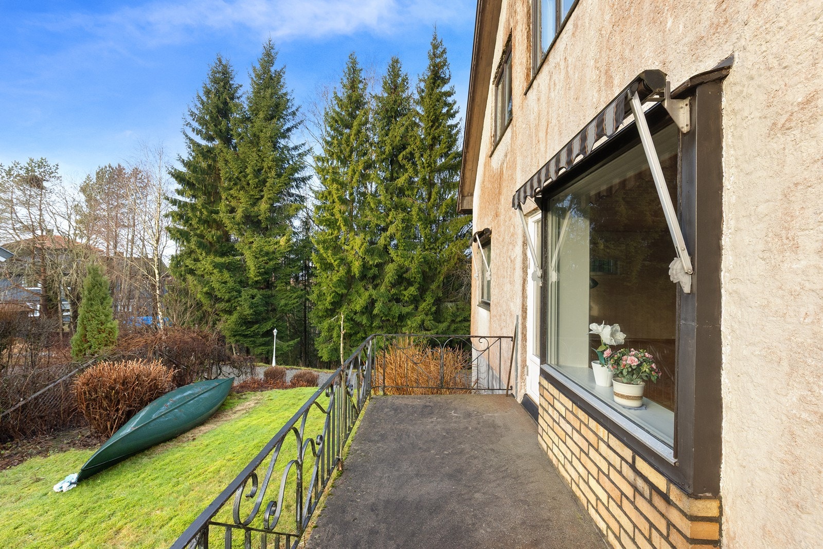 Balkong med betongdekke og smijernsrekkverk gir utsikt over hagen. Galleribilde