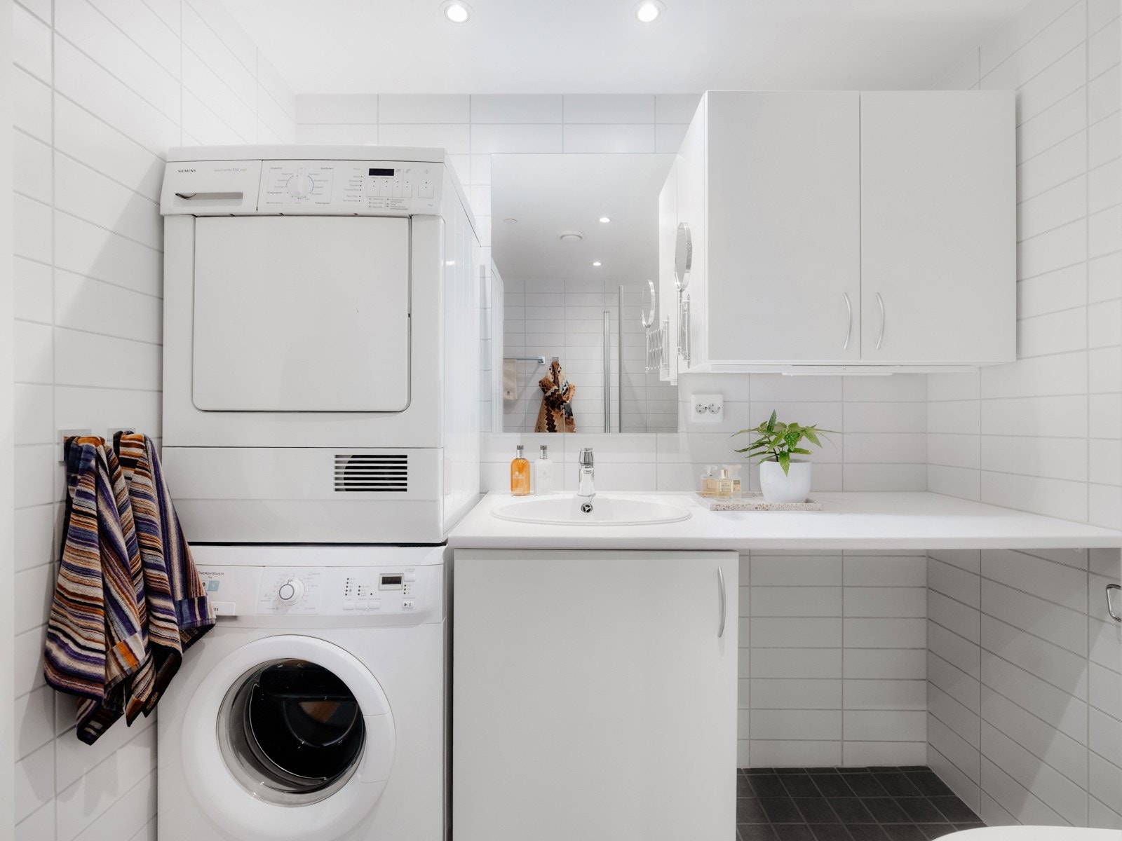 Det er opplegg for vaskemaskin og tørketrommel, og rommet er utstyrt med varmekabler i gulvet, spotlights i taket og mekanisk avtrekk. Galleribilde