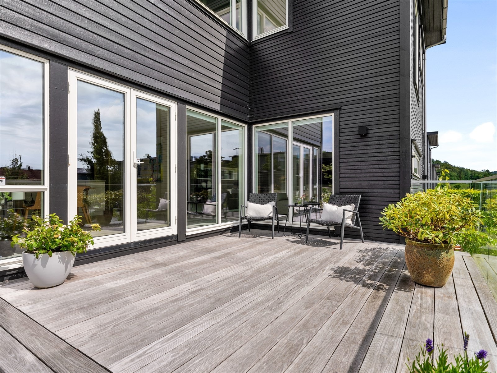 Innbydende, vedlikeholdsfri Kebony terrasse med glassrekkverk og flotte detaljer. Doble terrassedører forener kjøkken og spisestue med terrasse, og er det perfekte samlingssted en varm ettermiddag. Galleribilde