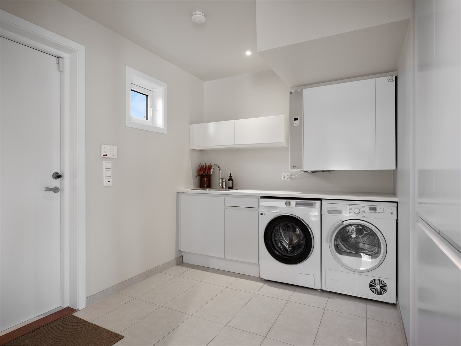 Lyst og lunt vaskerom/bi-inng med god lagring, i tilknytning til kjøkken. Praktisk når du skal sette på maskiner og lage mat samtidig. Ekstra greit når du kommer hjem fra tur og trening. Varmekabler i gulv. Galleribilde