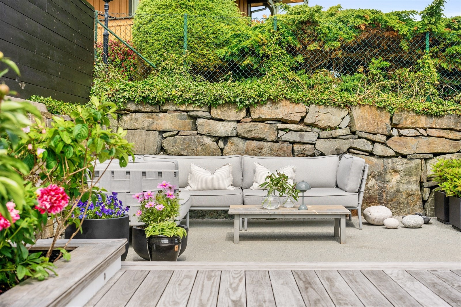 Lunt, skjermet og solrikt. Pene kontraster mellom Kebony, støpt platting og plen. Innrammet bed på terrassen med flotte buskvekster. Galleribilde