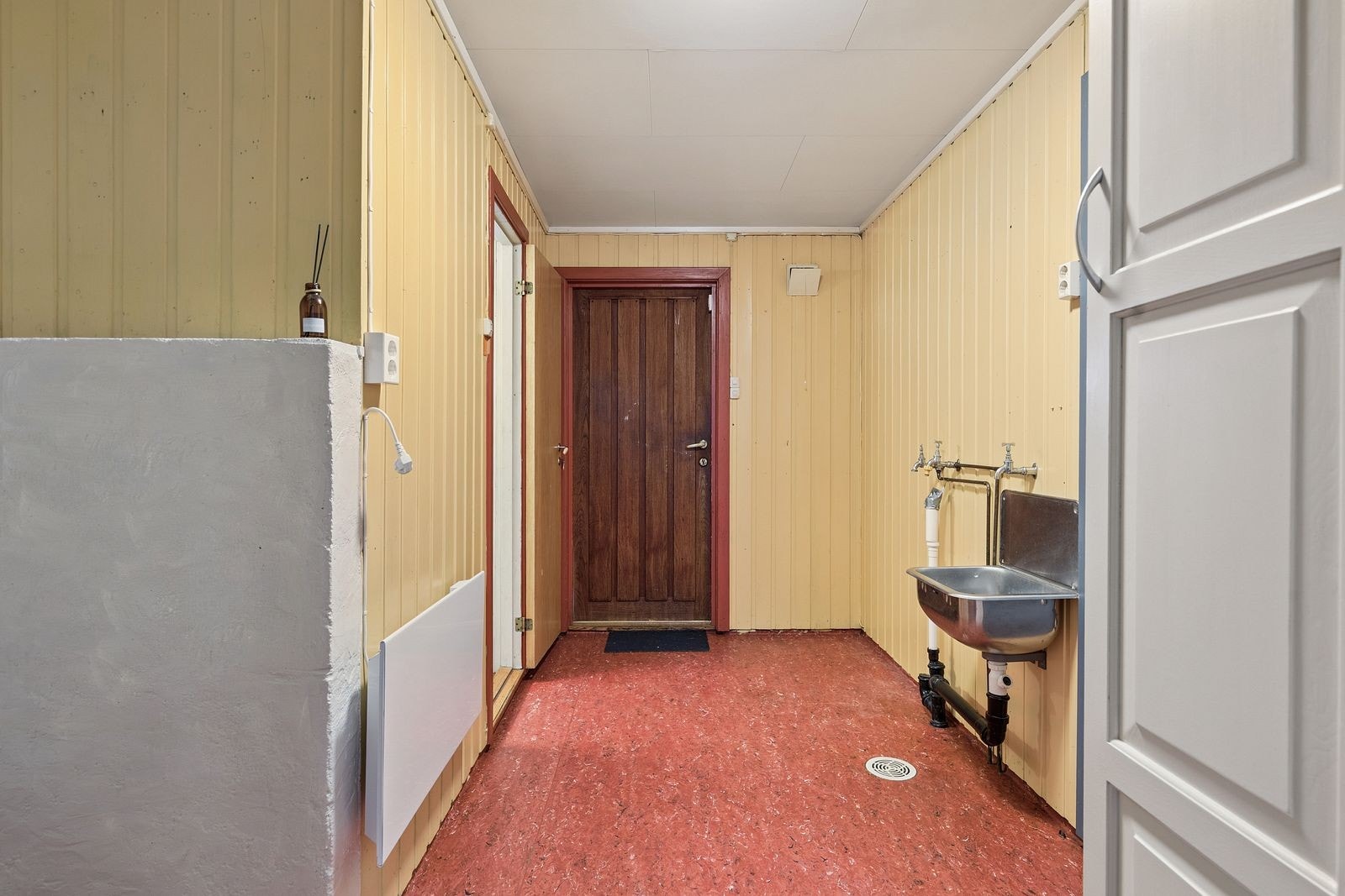 Gang med opplegg for vaskemaskin, direkte adkomst til baderom og utgang til husets bakside. Galleribilde