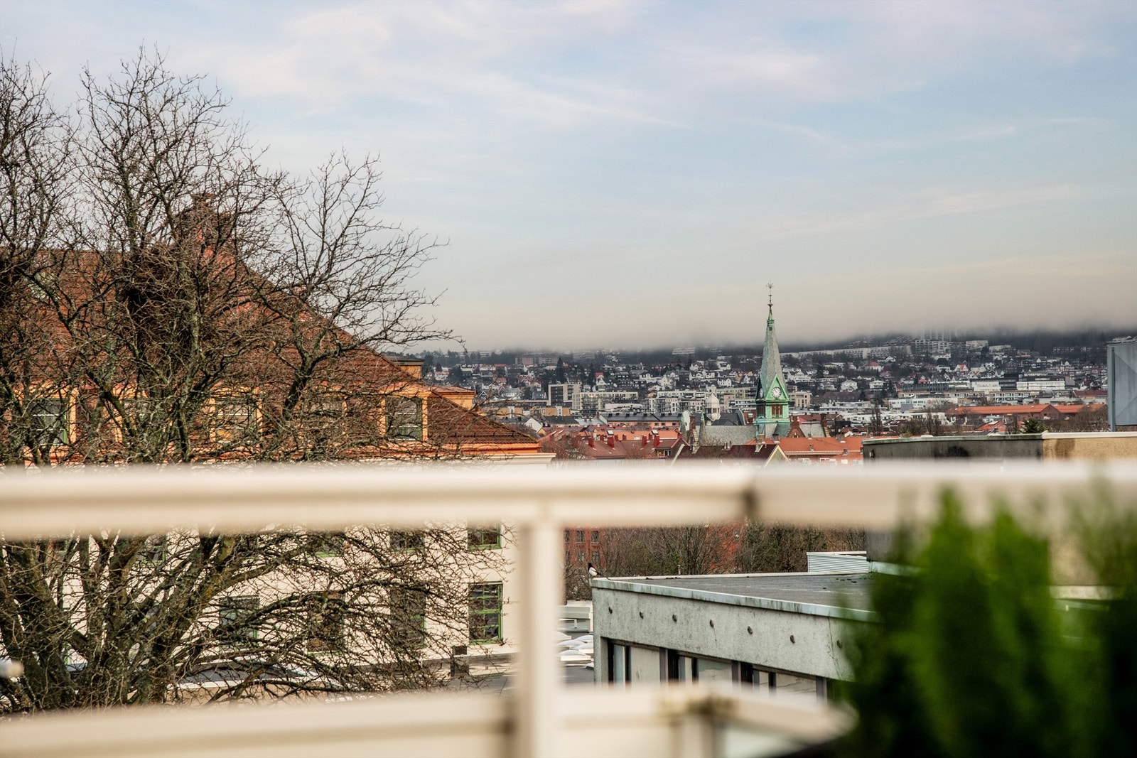 Balkongen har flott utsikt over store deler av byen. Her ser man taket på bygninger, mot mark og mye himmelsyn. Galleribilde