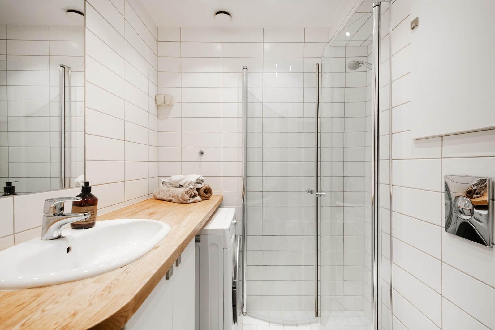 Pent flislagt bad som byr på servant med underskap, vegghengt toalett, gulvvarme og opplegg til vaskemaskin. Galleribilde