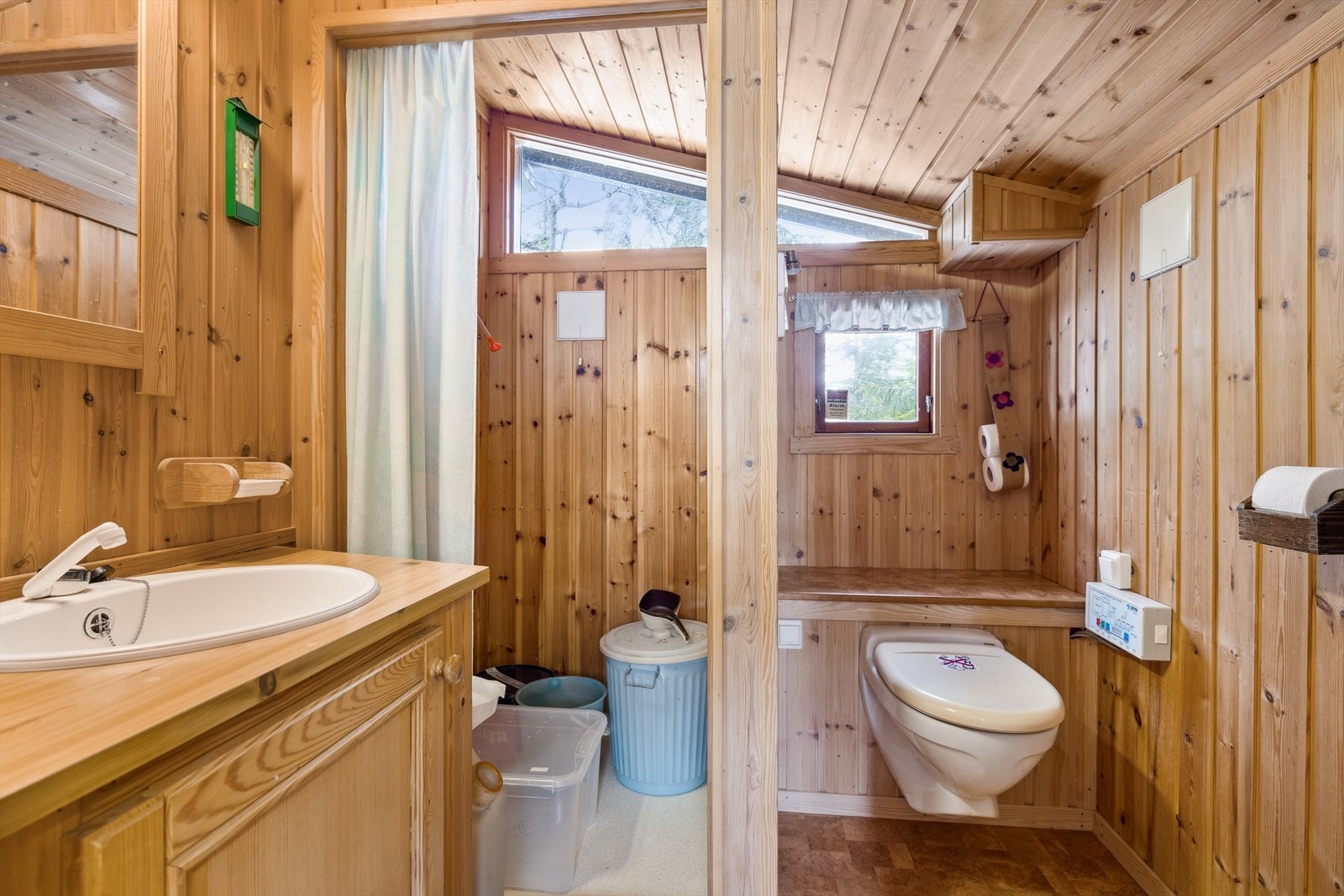 Rommet har belegg på gulv og panel på vegger. Badet er innredet med en stor baderomsinnredning med servant, speil, dusjsone med campingdusj og vakumtoalett. Galleribilde