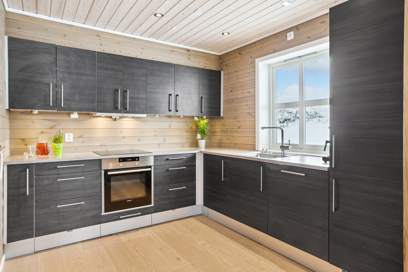 Pent HTH kjøkken med glatte mørke fronter, integrerte hvitevarer, gulvvarme og downlights. Galleribilde