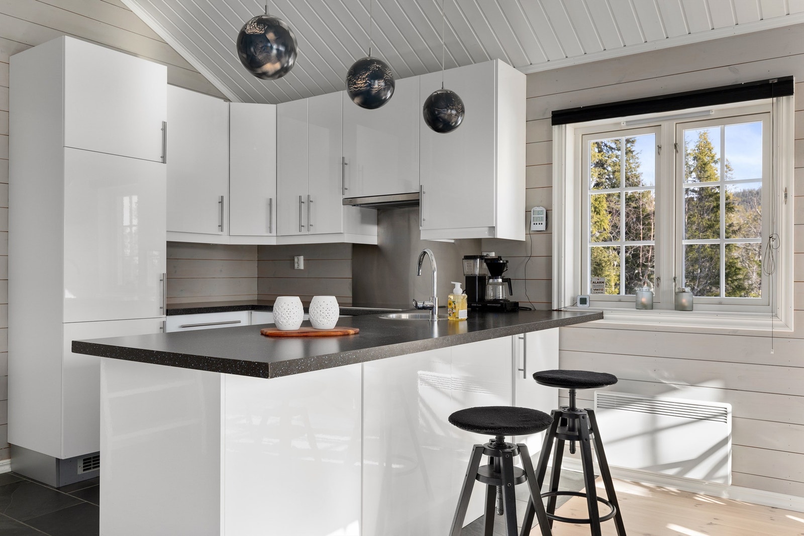 Kjøkkenhalvøy som gir et naturlig skille mellom kjøkken og spisestue i tillegg til ekstra skap- og benkeplass Galleribilde