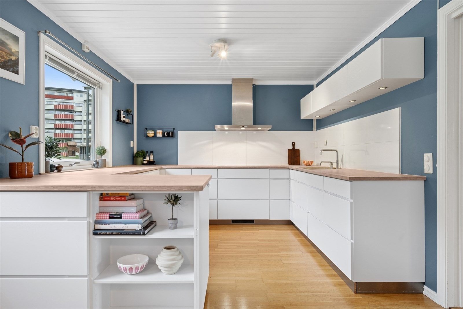 Kvik kjøkkeninnredning fra 2014 med hvite slette kjøkkenfronter og integrerte dørhåndtak. Benkeplate i solid treverk, med underlimt vask. Galleribilde