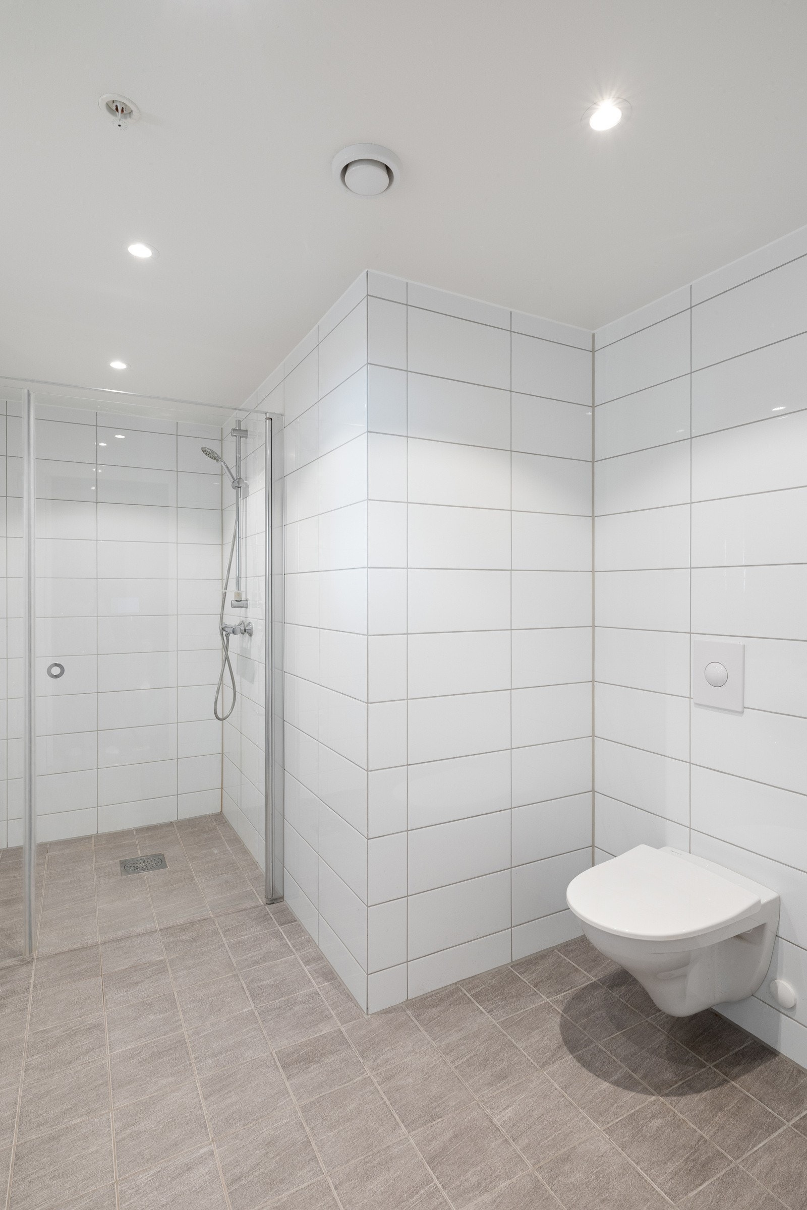 Badet er innredet med seksjon med hel servant, vegghengt toalett med skjult sisterne og glassvegg i dusj. Galleribilde