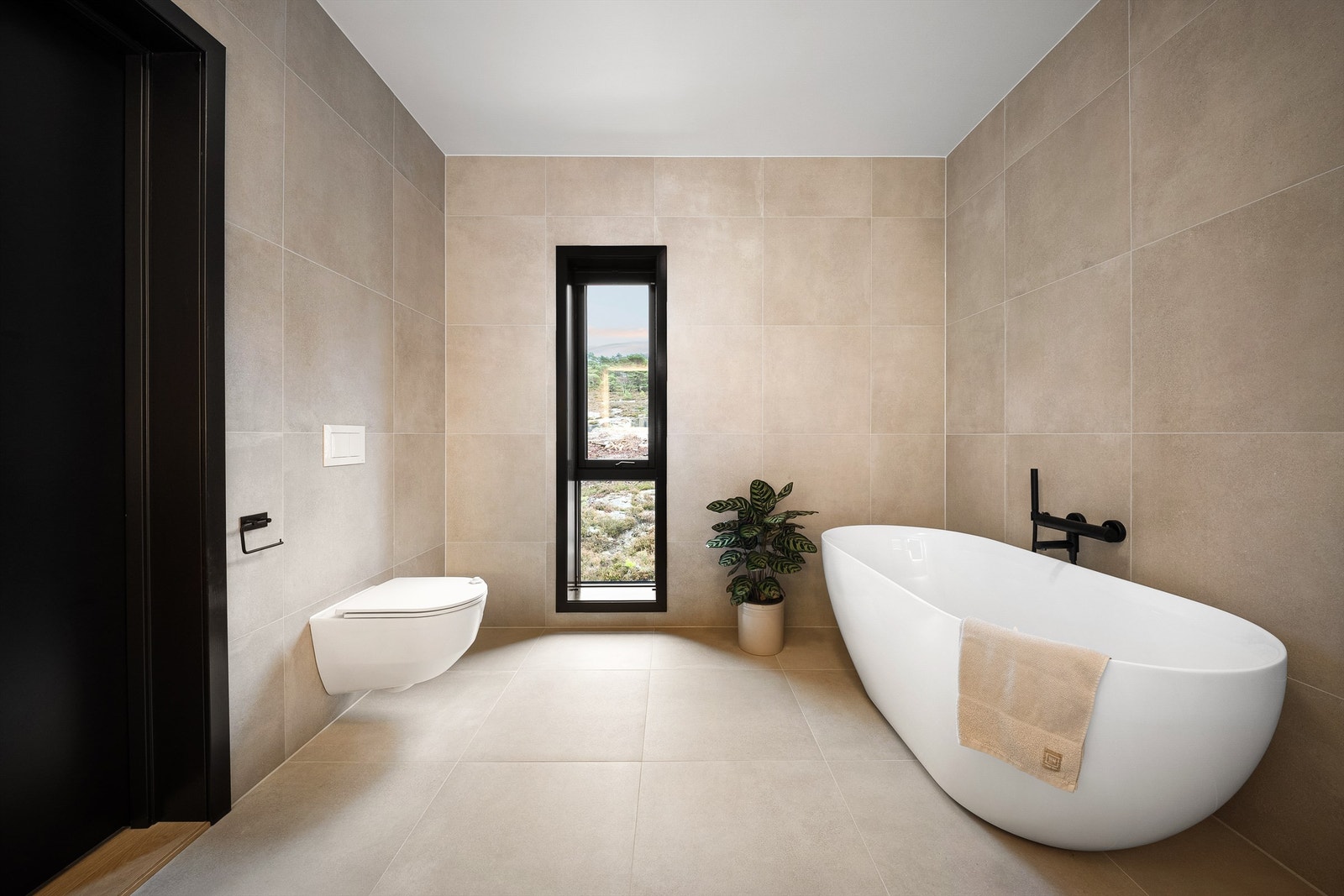 Storformat fliser i varme nyanser på både gulvet og veggene gir badet helhet. Plisségardin er montert i vinduet. Galleribilde