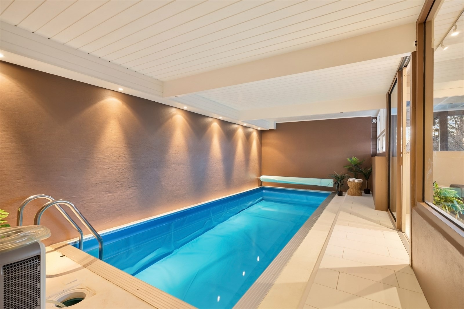 Fra peisestuen kommer man inn til bassengrommet med fliser rundt bassenget, malte pussede murvegger og panel i himlingen med spotter som lyskilde. Bassenget er på ca. 7 x 3 meter (21 kvm), med en dybde på ca. 1,6 meter iht. tidligere salgsoppgave. Galleribilde