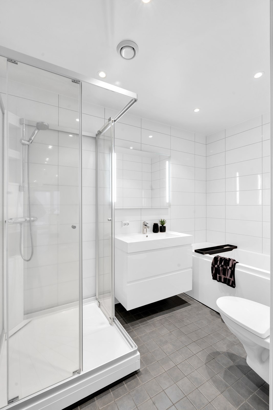 Lekkert og komplett flislagt bad med moderne og praktiske innredninger. Galleribilde