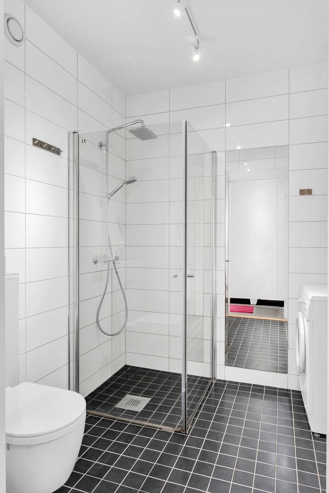 Komplett flislagt bad med praktisk innfellbar dusjnisje og vegghengt toalett. Galleribilde