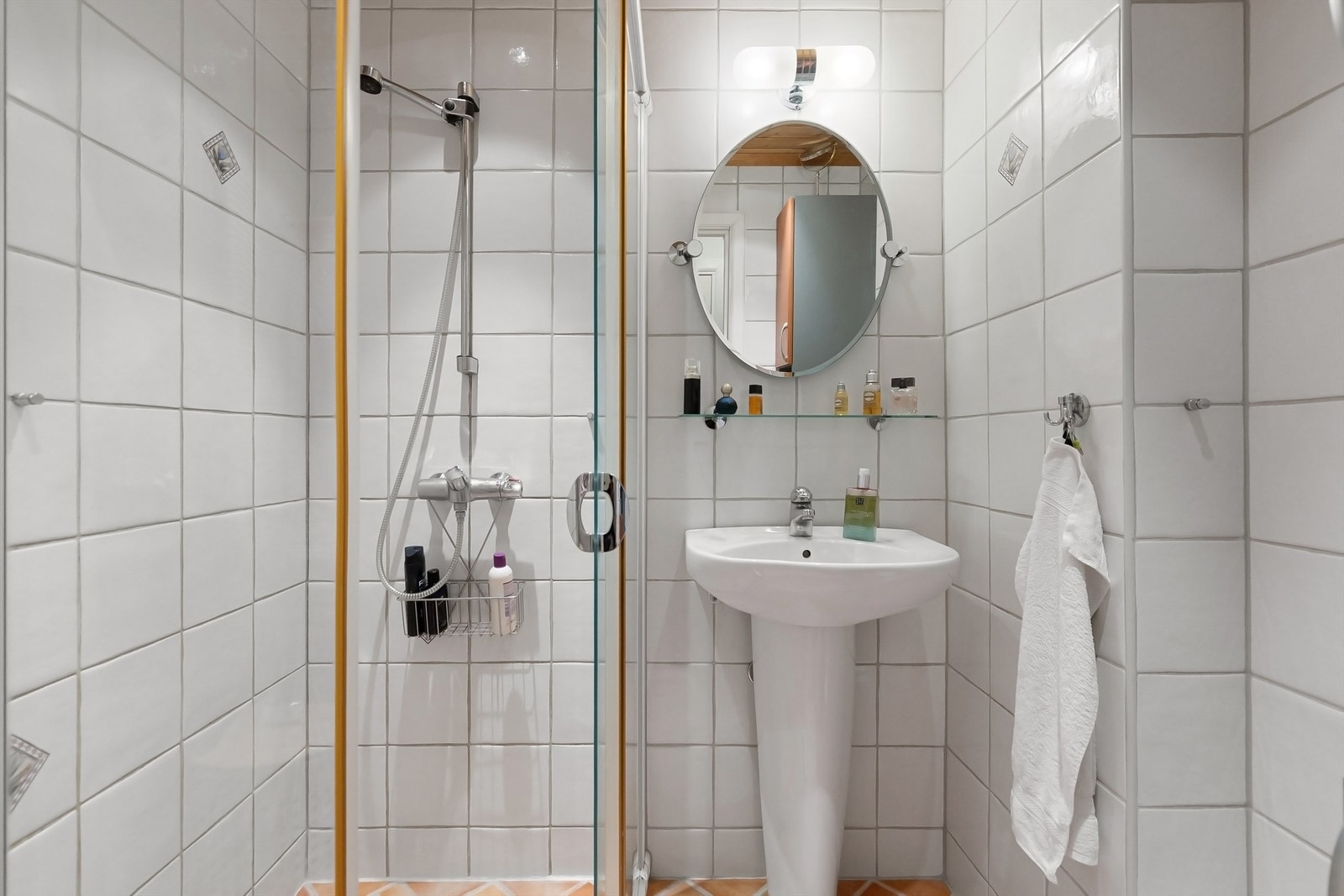 Rommet er utstyrt med dusjhjørne med skyvedører, servant og speil med belysning. Galleribilde