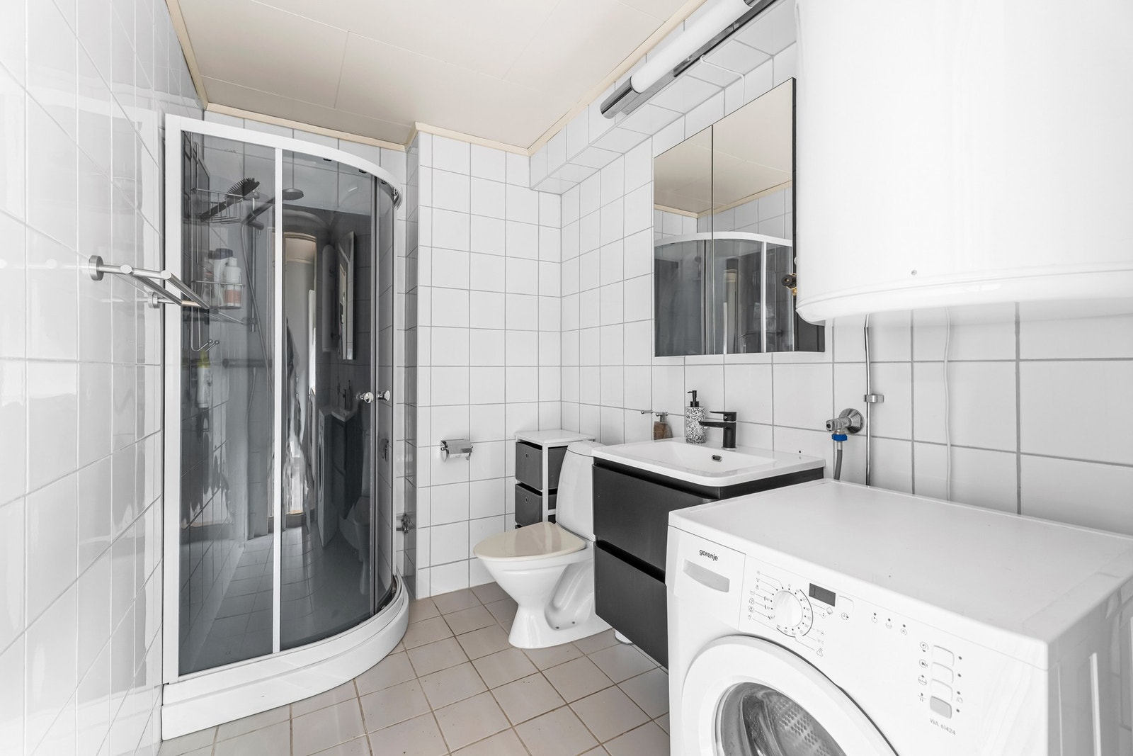 Flislagt baderom med dusjnisje og opplegg for vaskemaskin. Galleribilde