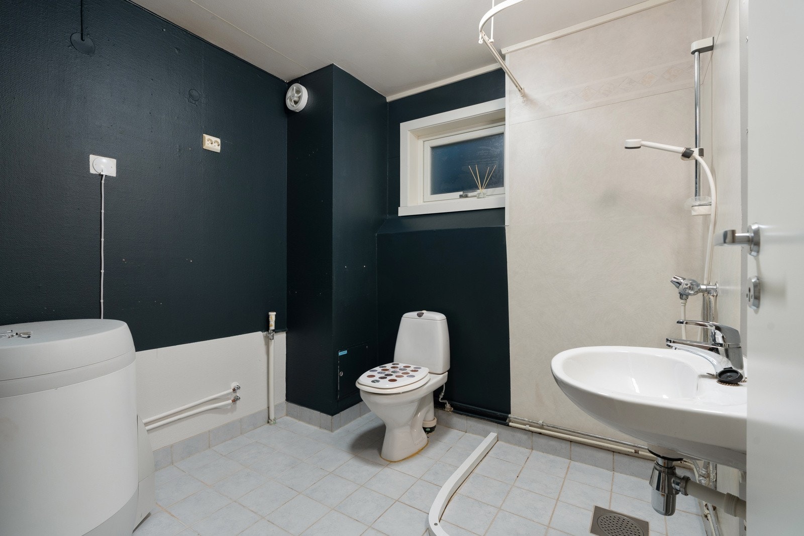 Bad/wc/vaskerom med fliser på gulv og dusjhjørne. Galleribilde