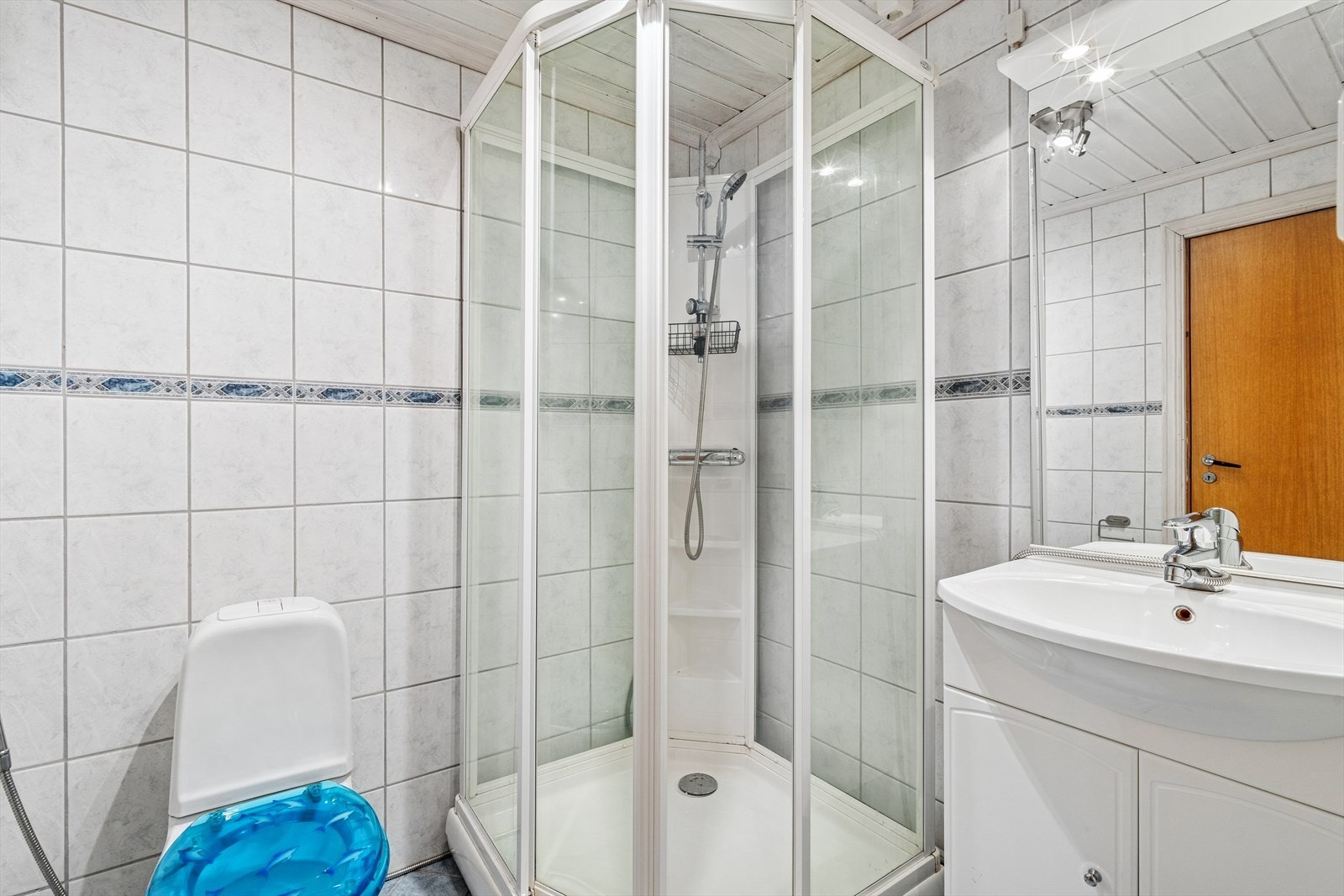 Baderom i underetasjen har gulv-montert toalett, dusjkabinett, og servant i innredning. Galleribilde