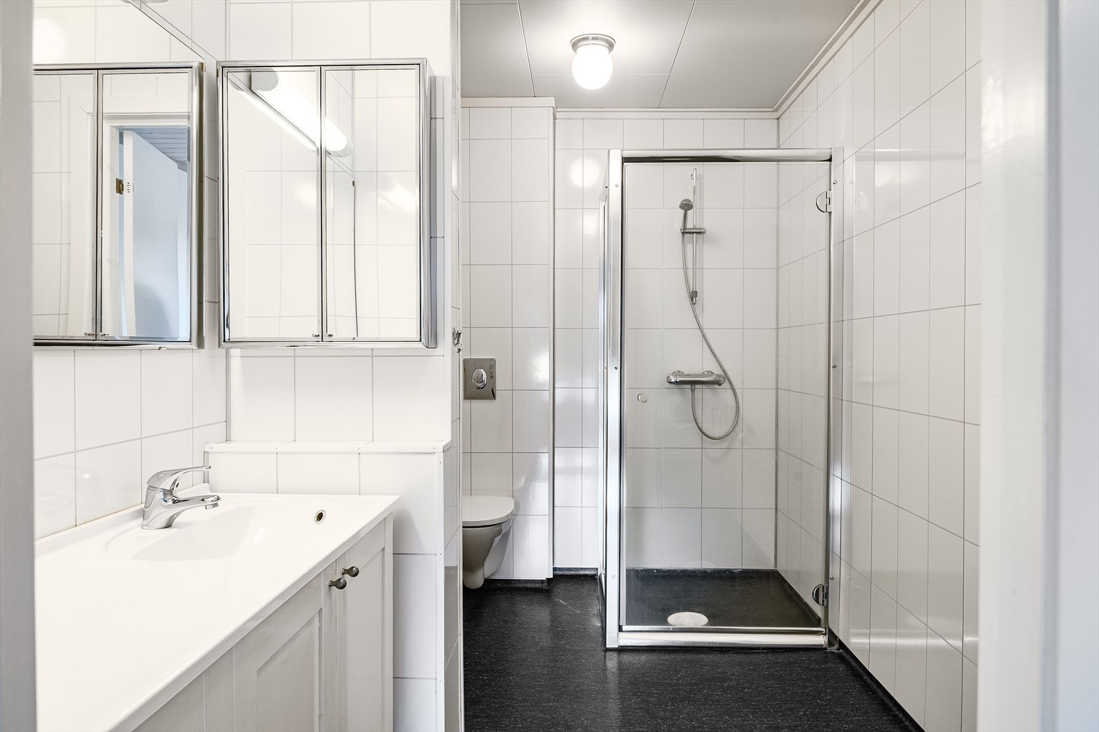 Badet innenfor hovedsoverommet har vinyl på gulv og baderomsplater på vegger. Baderommet er innredet med heldekkende servant nedfelt i romslig baderomsinnredning, speilskap, dusjhjørne og vegghengt toalett. Galleribilde