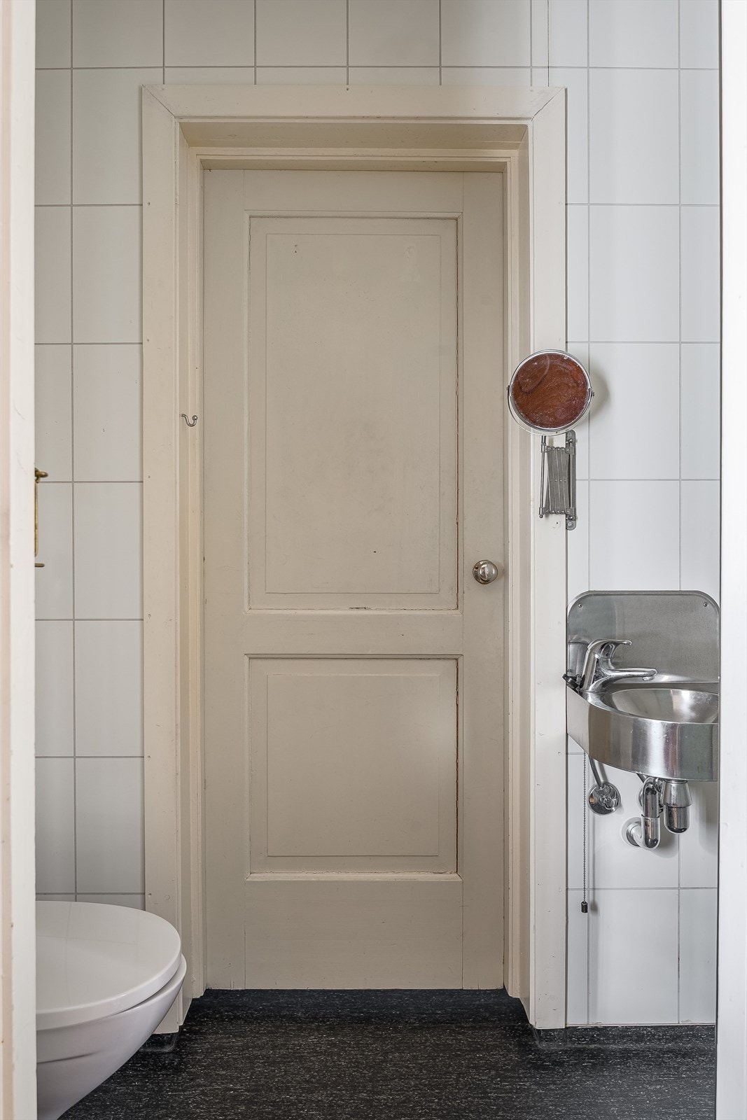 Toalettrommet er innredet med vinyl på gulv og baderomsplater på vegger, og inneholder frittstående toalett og vegghengt stålservant. Enkel til gang til praktisk vaskerom bak toalettrommet. Galleribilde