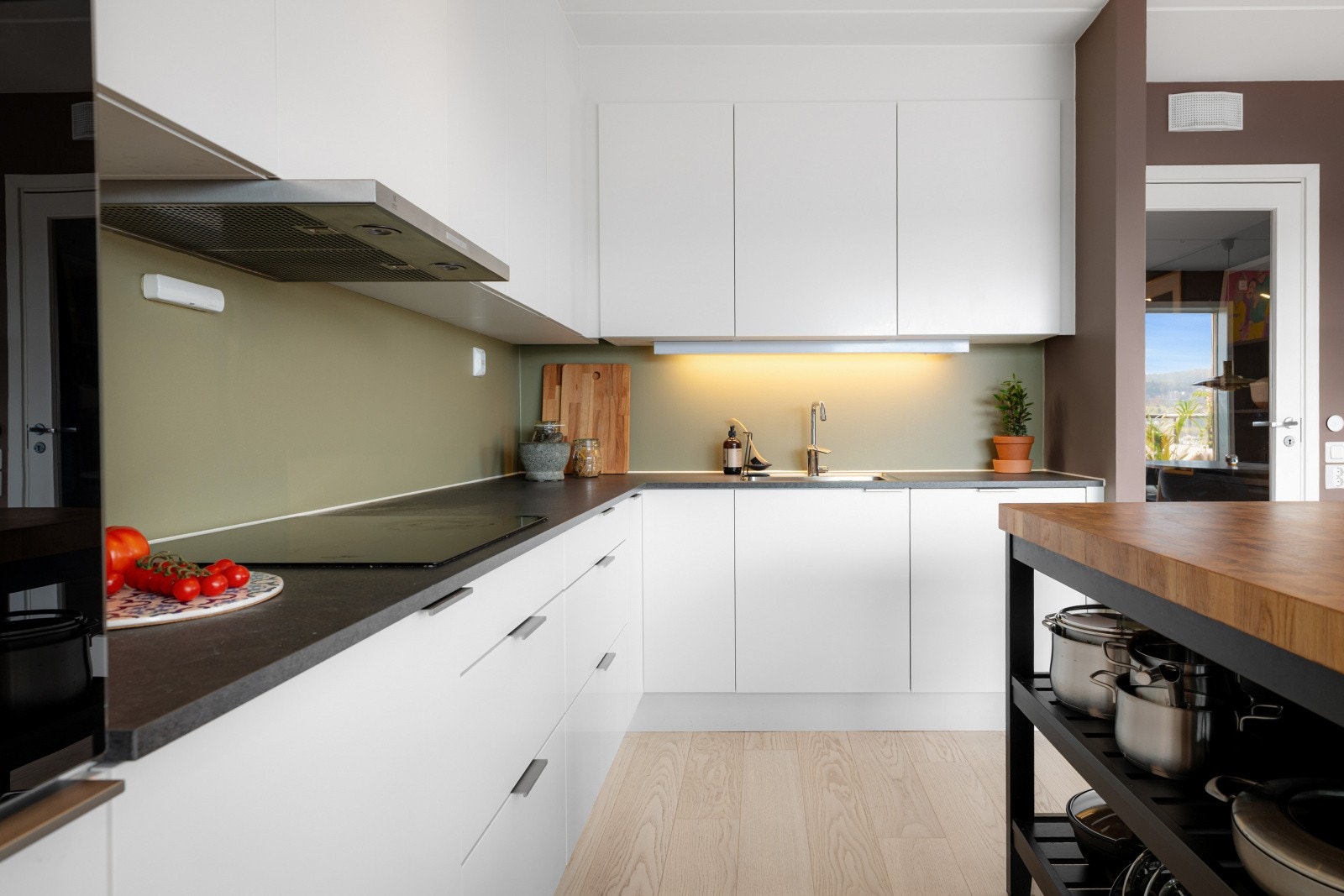 De integrerte hvitevarene inkluderer en praktisk induksjonsplatetopp, stekeovn, oppvaskmaskin, og kjøle- og fryseskap. Galleribilde