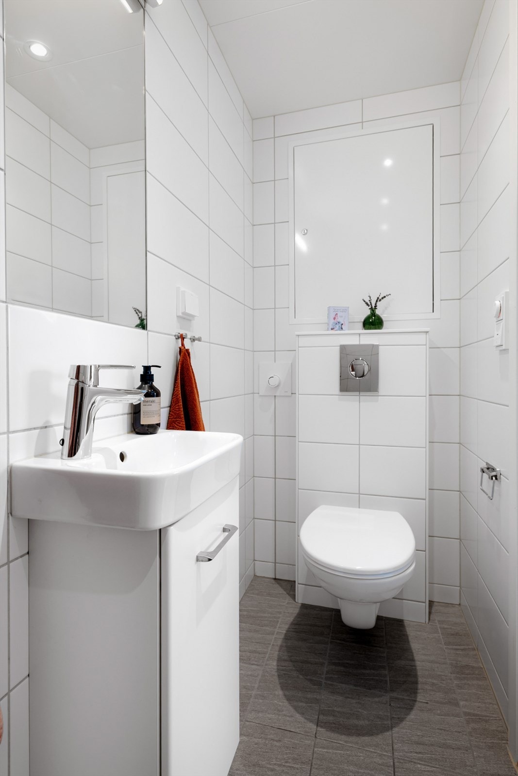 Badet inneholder: Servantskap med glatte, folierte fronter og heldekkende servant, innmurt speil og lysarmatur på vegg over servant. Galleribilde