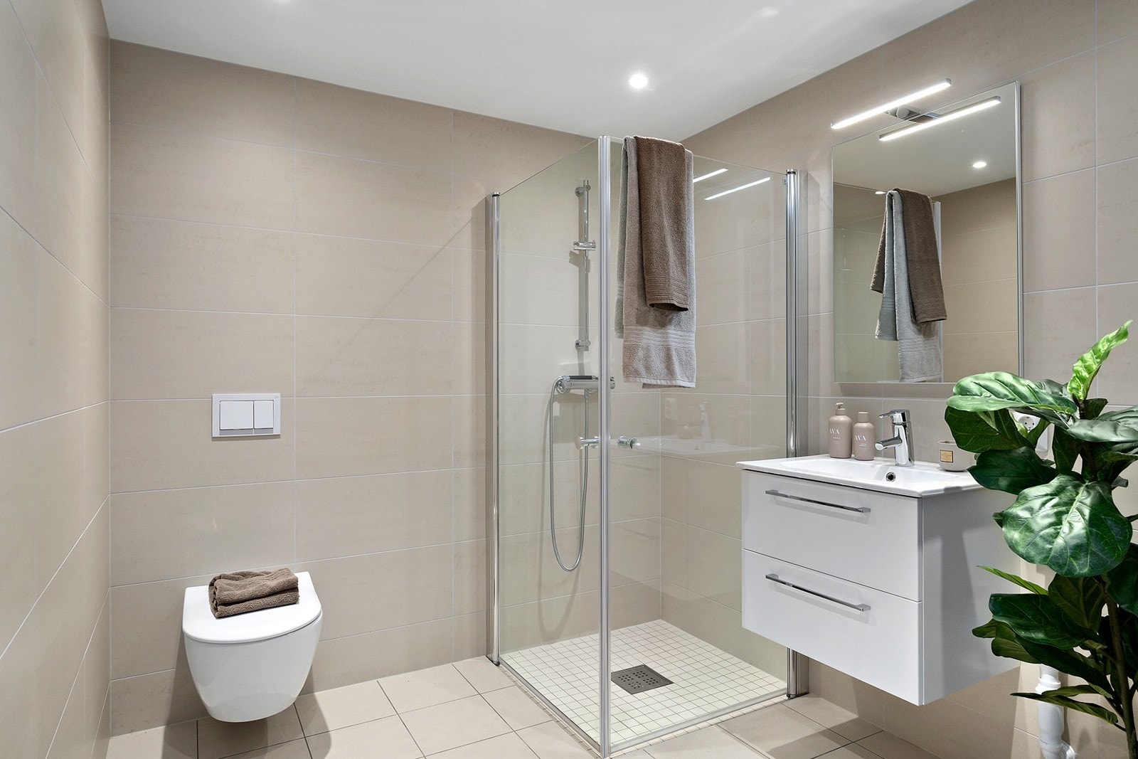 Flislagt bad med varme i gulv, og nedsenket himling med downligths. Galleribilde