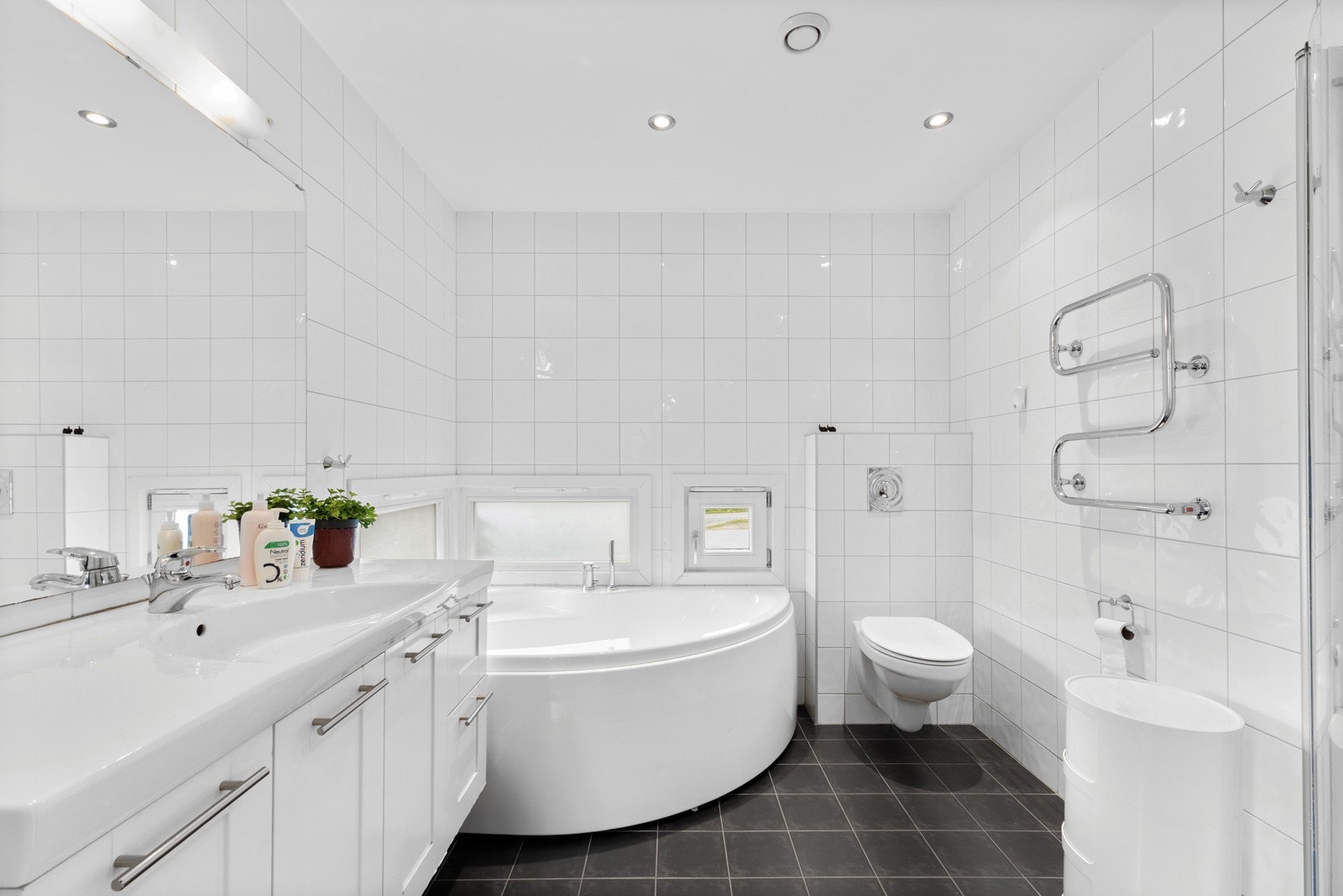 Innbydende baderom med mørke fliser og komfortabelt badekar Galleribilde