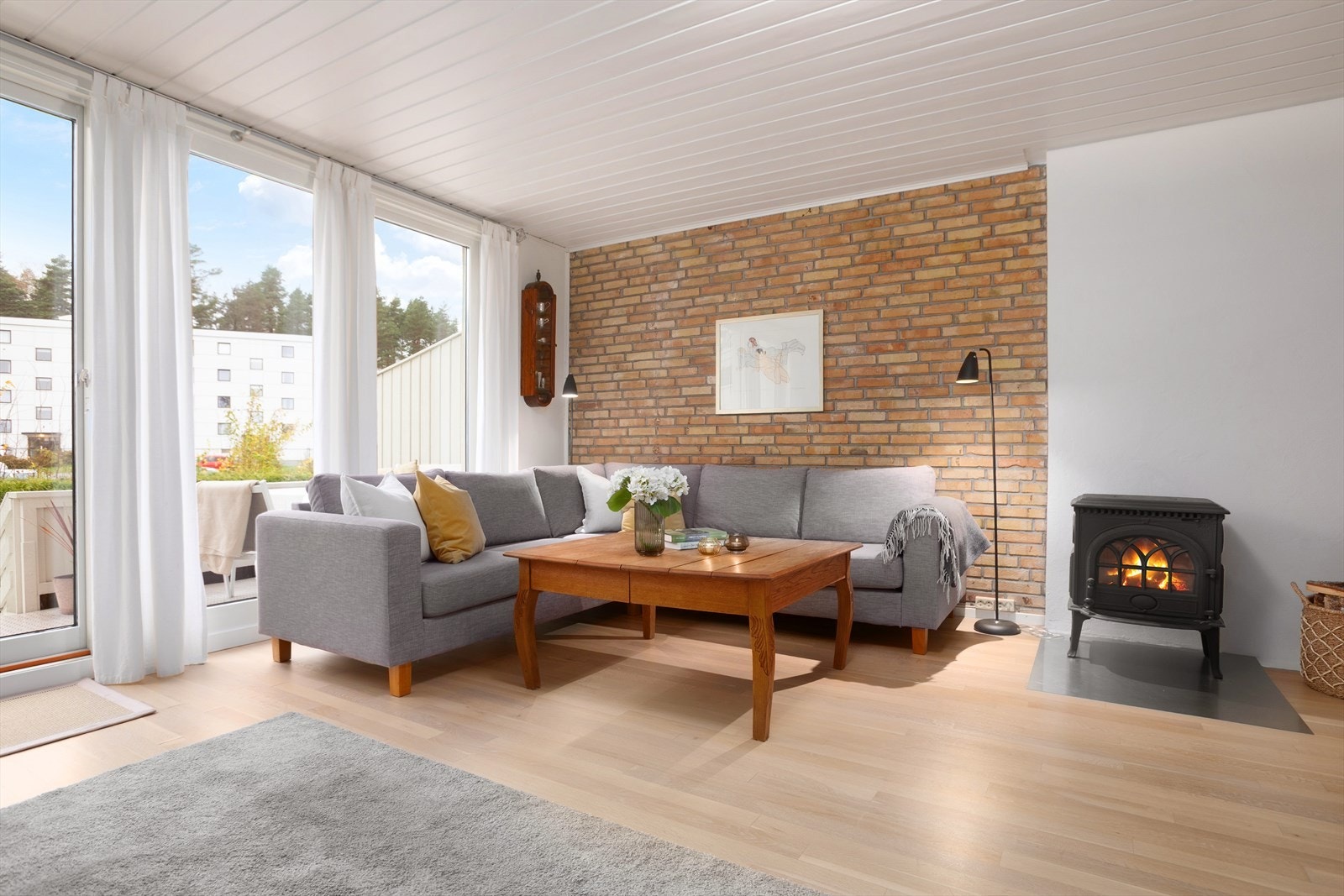 Det er peis i stue som bidrar til en lun atmosfære i oppholdsrommet - teglstensveggen gir ett røft preg i rommet Galleribilde