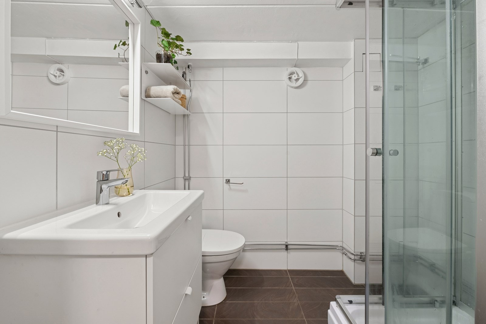 Pent flislagt baderom i kjelleretasje fra 2012 med elektriske varmekabler i gulv og malt himling. Det er en pen innredning, speil med belysning, klosett og et dusjkabinett. Galleribilde