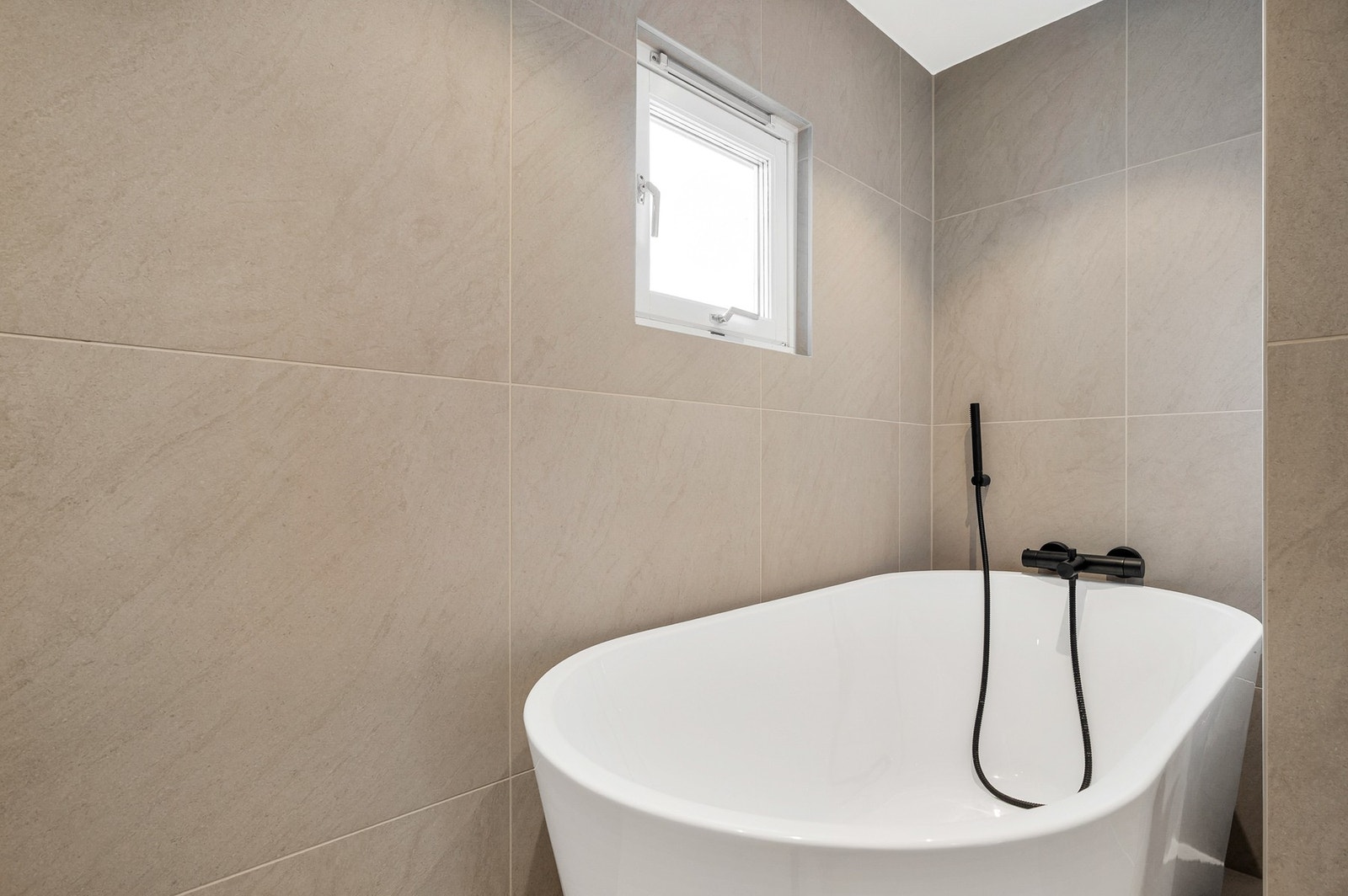 Pent frittstående badekar med sort armatur Galleribilde